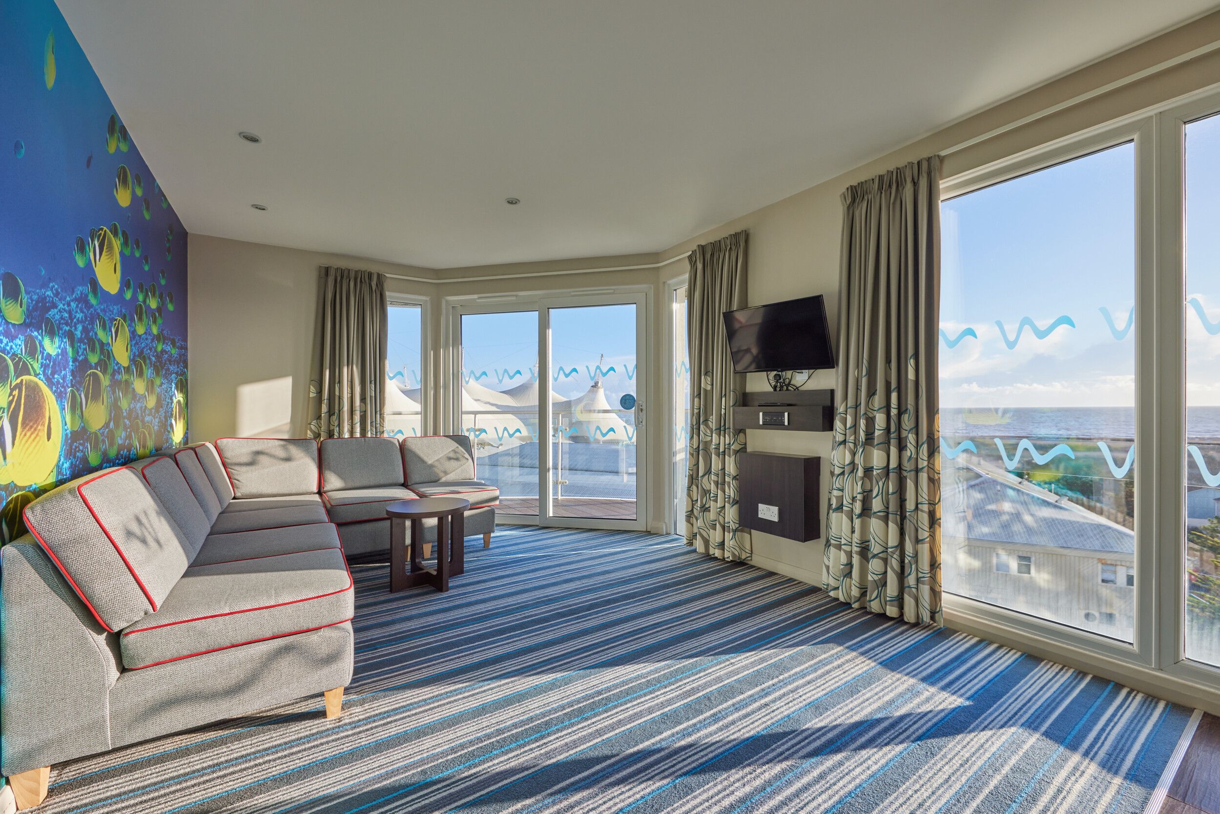 A living room with sofas, coffee table and TV in our Wave Hotel Apartments at Bognor Regis.