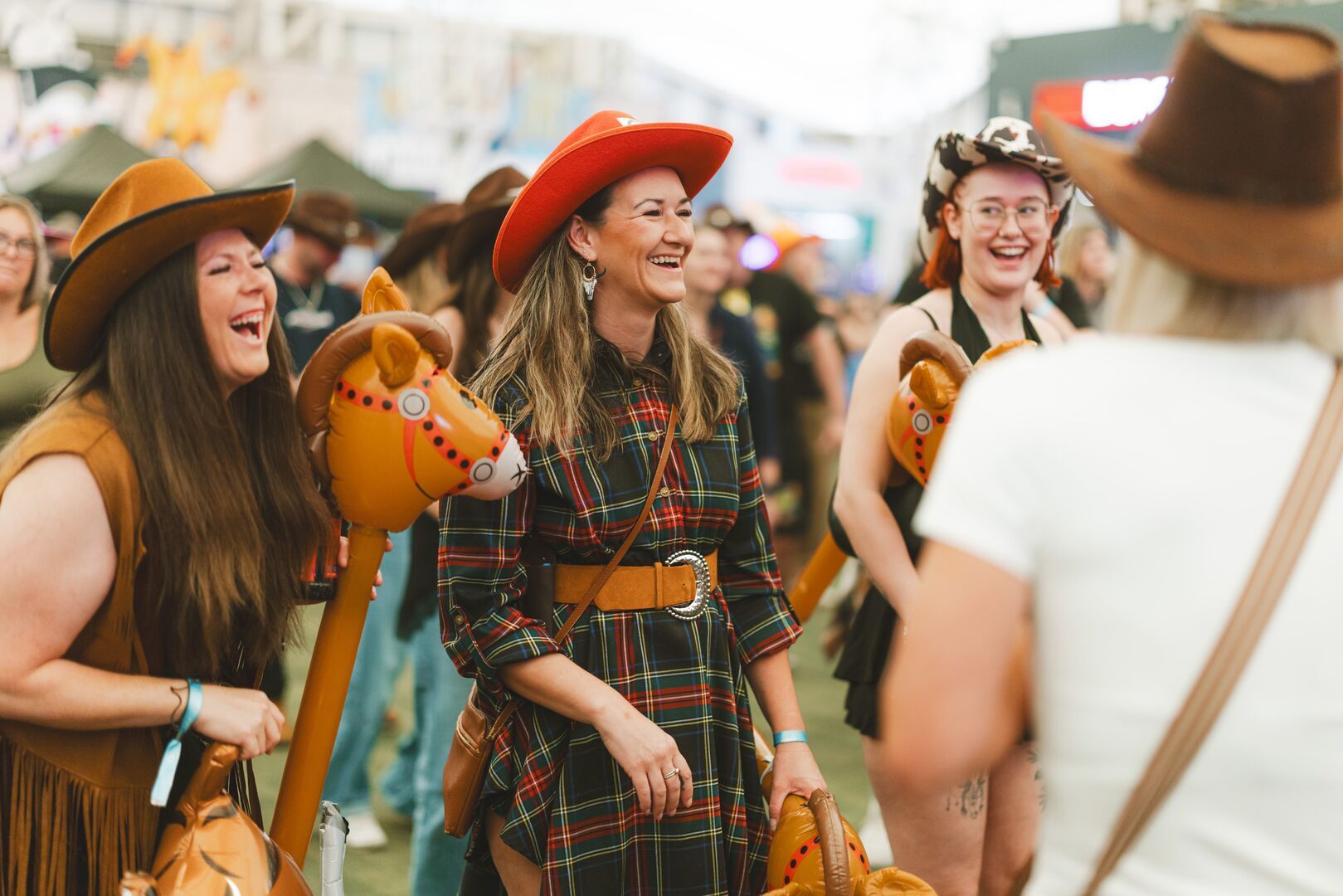 A group of friends in cowboy hats with blow-up horses, enjoying the Saddle Up activity at Minehead resort.
