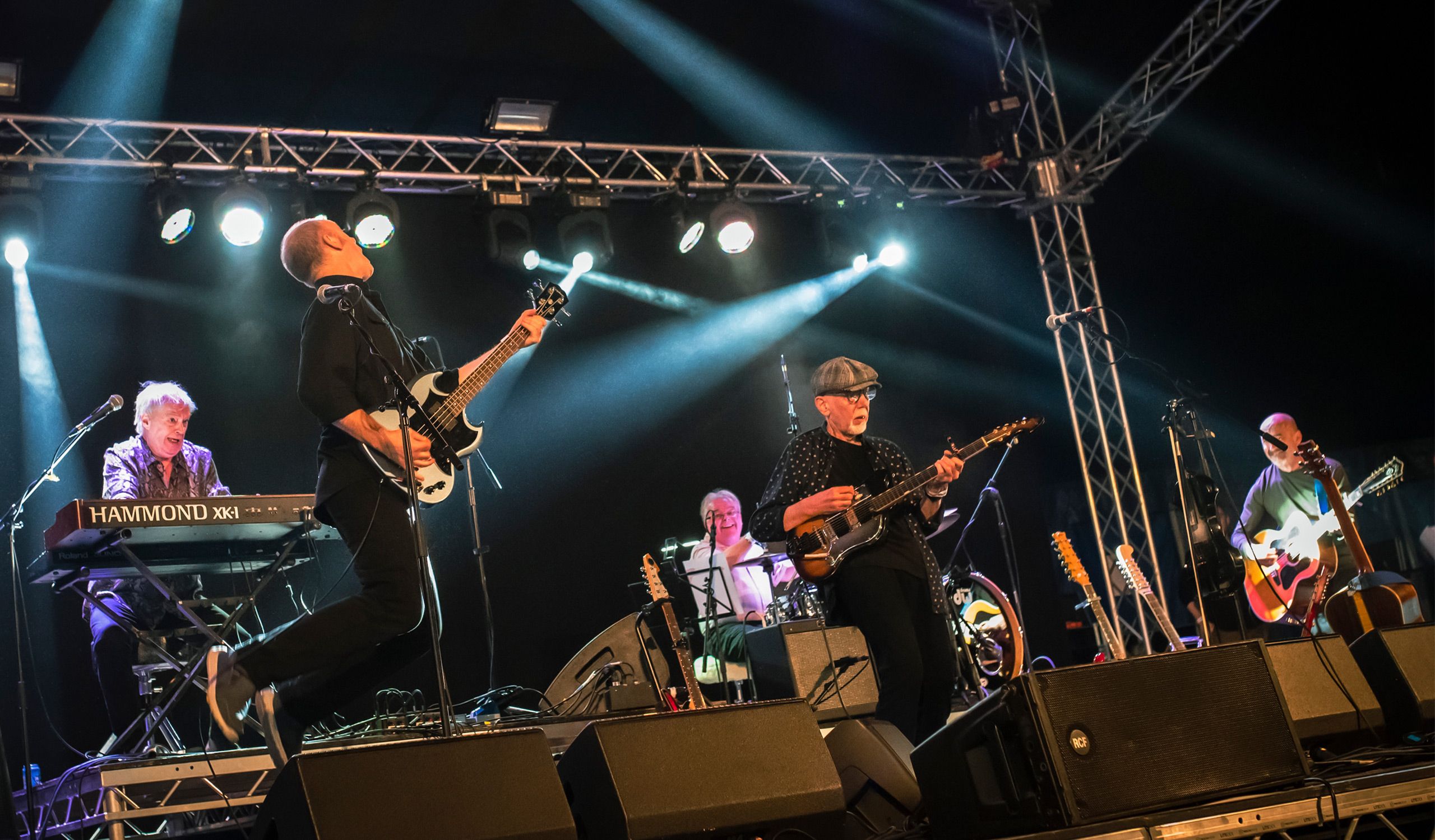 The members of Lindisfarne playing their instruments on stage.