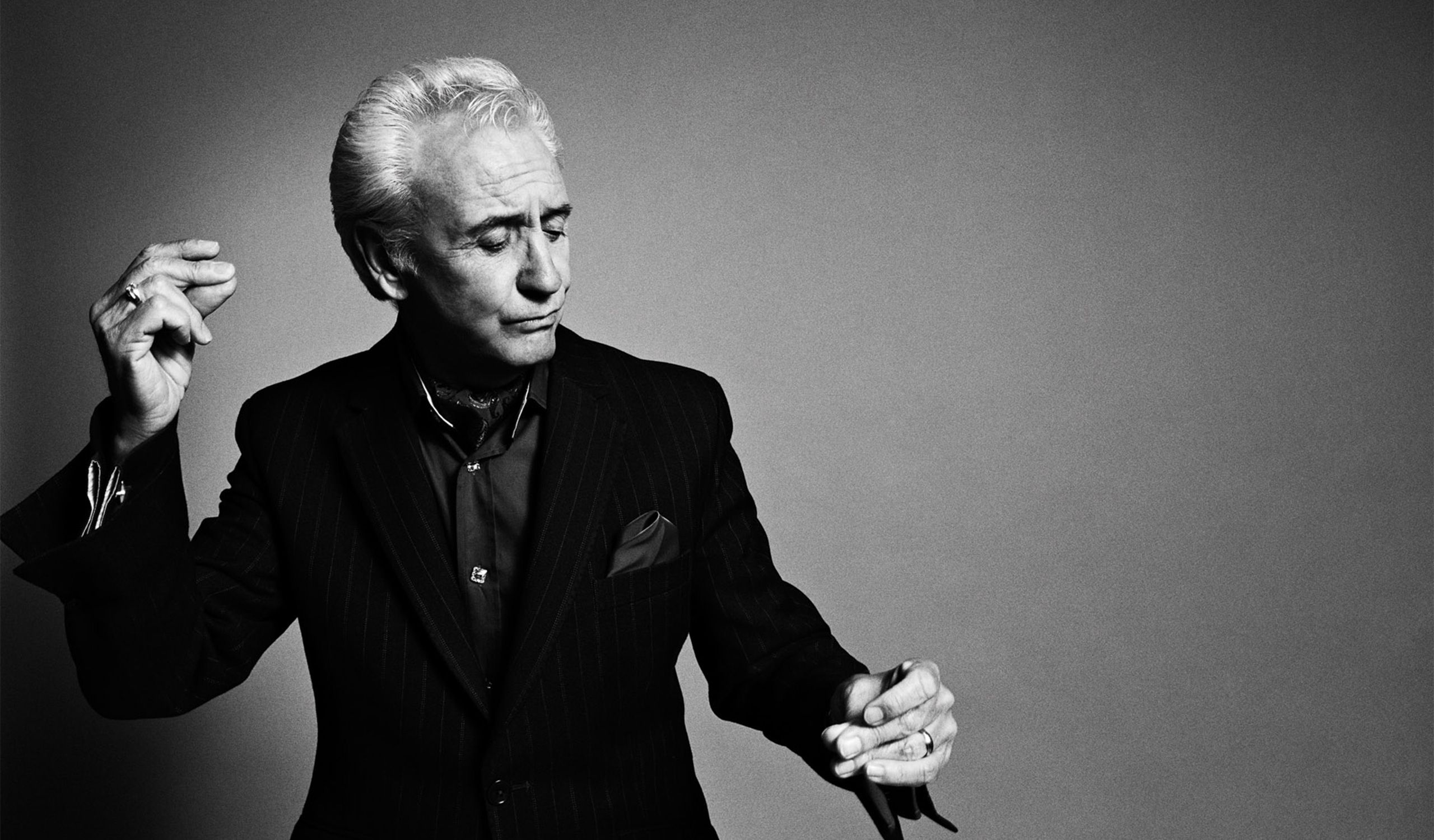 A black-and-white image of Tony Christie in a suit, dancing and snapping his fingers.