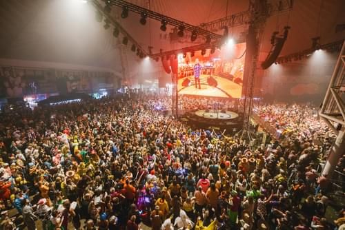 A photo of a large crowd at the Fatboy Slim All Back to Minehead weekender, with Fatboy Slim himself on stage.