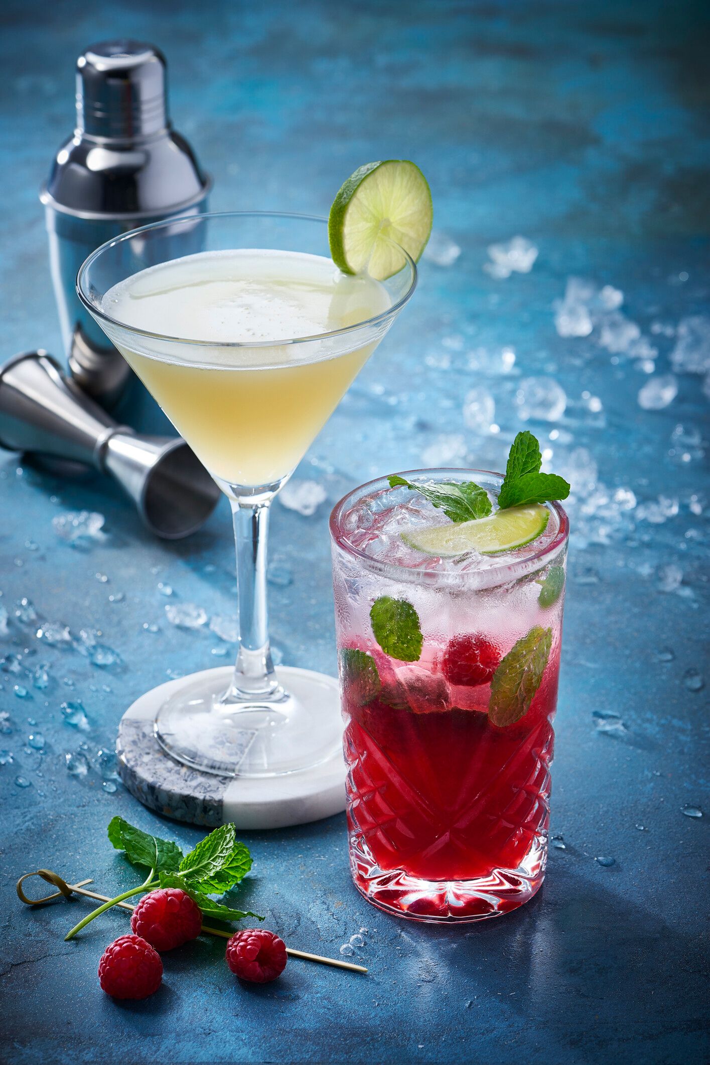 Two glasses of cocktail garnished with mint and lemon.