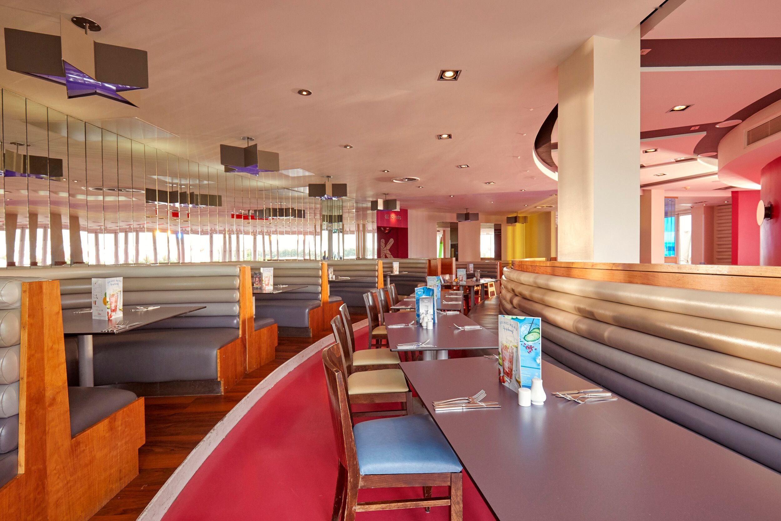 An empty dining area with condiments and cutleries on the table.