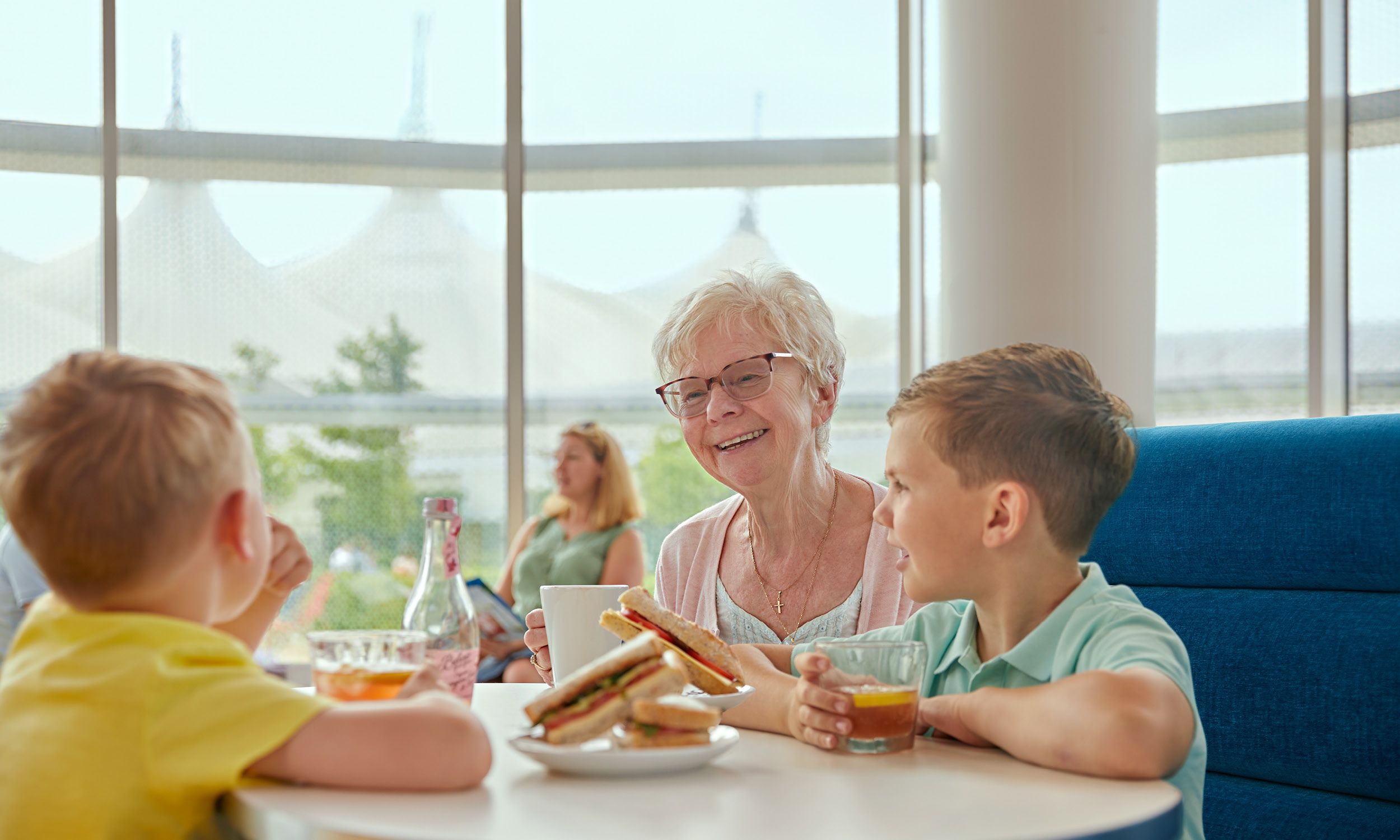 A Grandmother sits with her grandsons as they eat at a Butlin's restaurant.