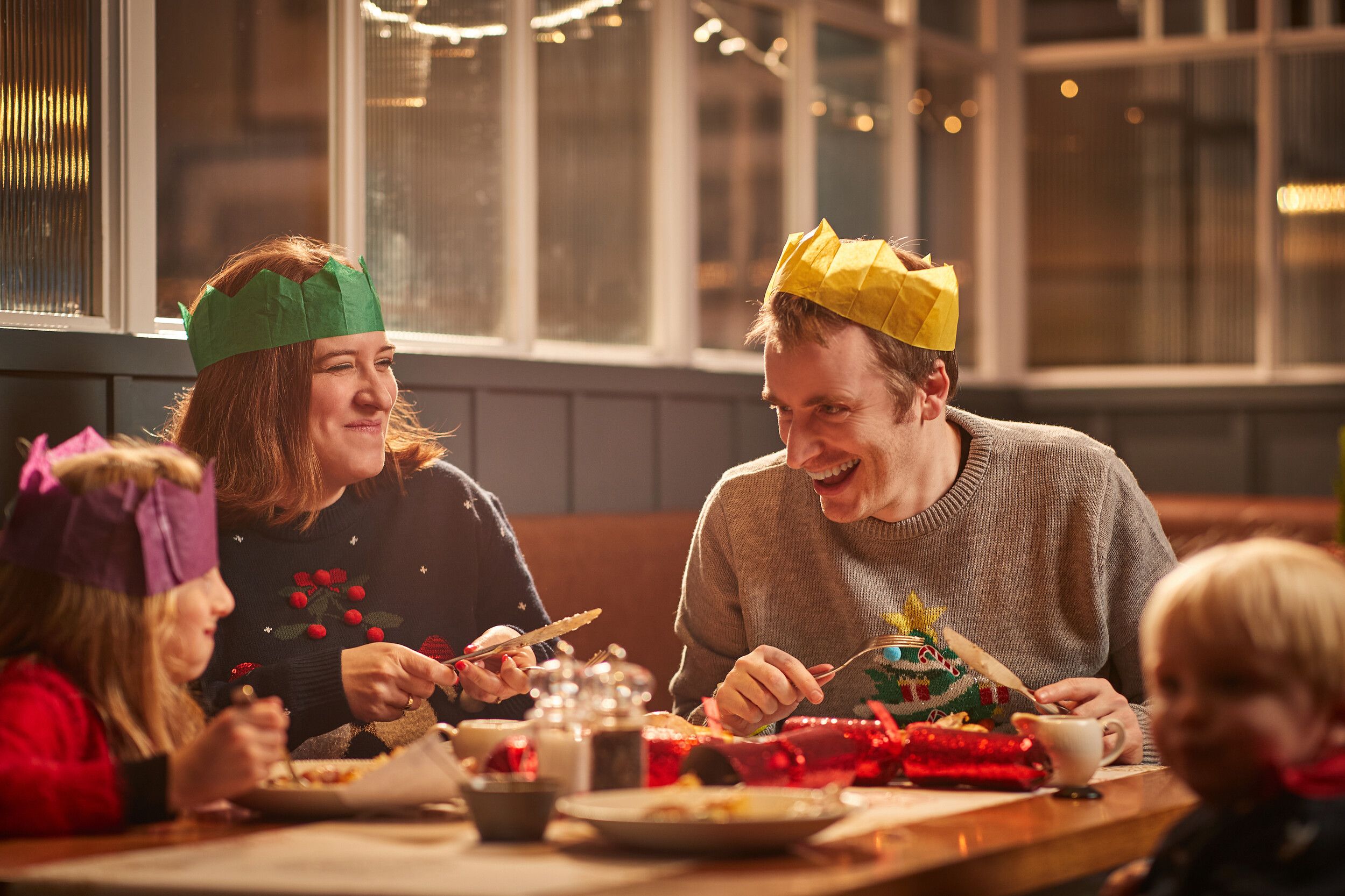 A family of four having a Christmas dinner around the dining table.