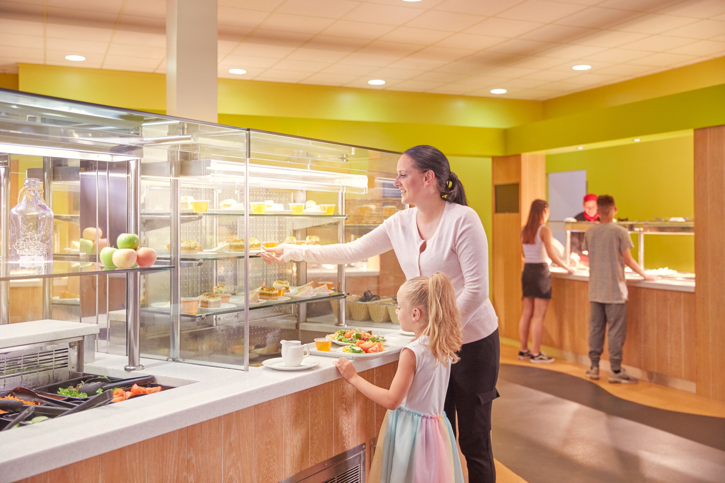 A mother and her daughter taking some cake from the chiller.
