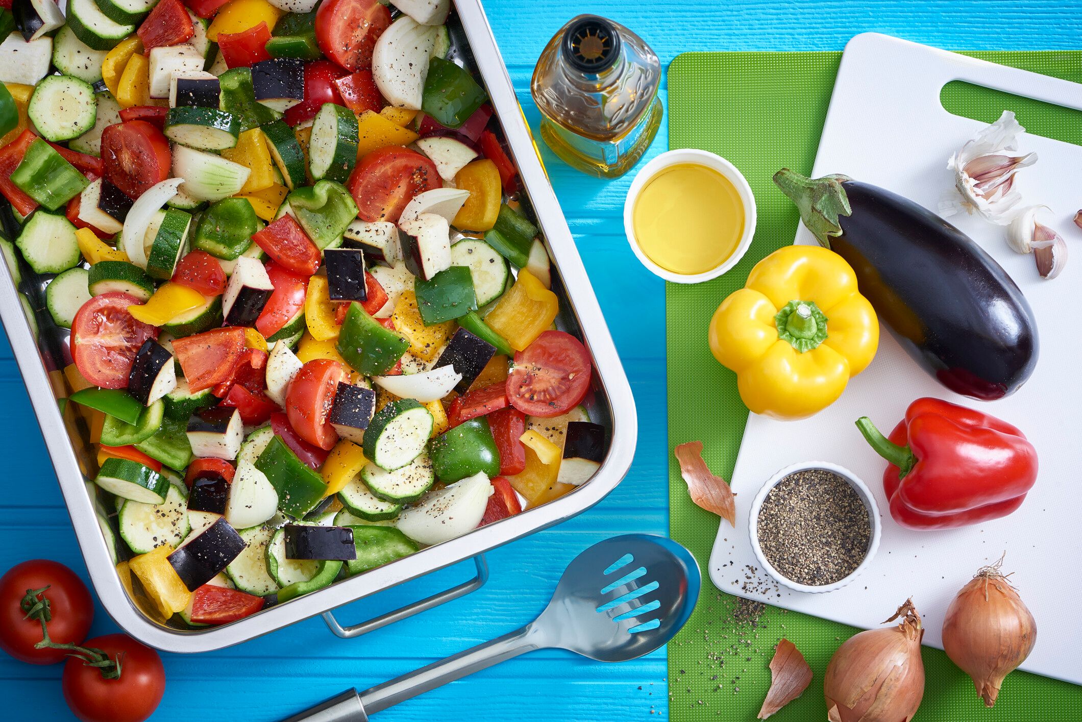 A table with a food container filled with tomatoes, cucumbers, onions and bell peppers.