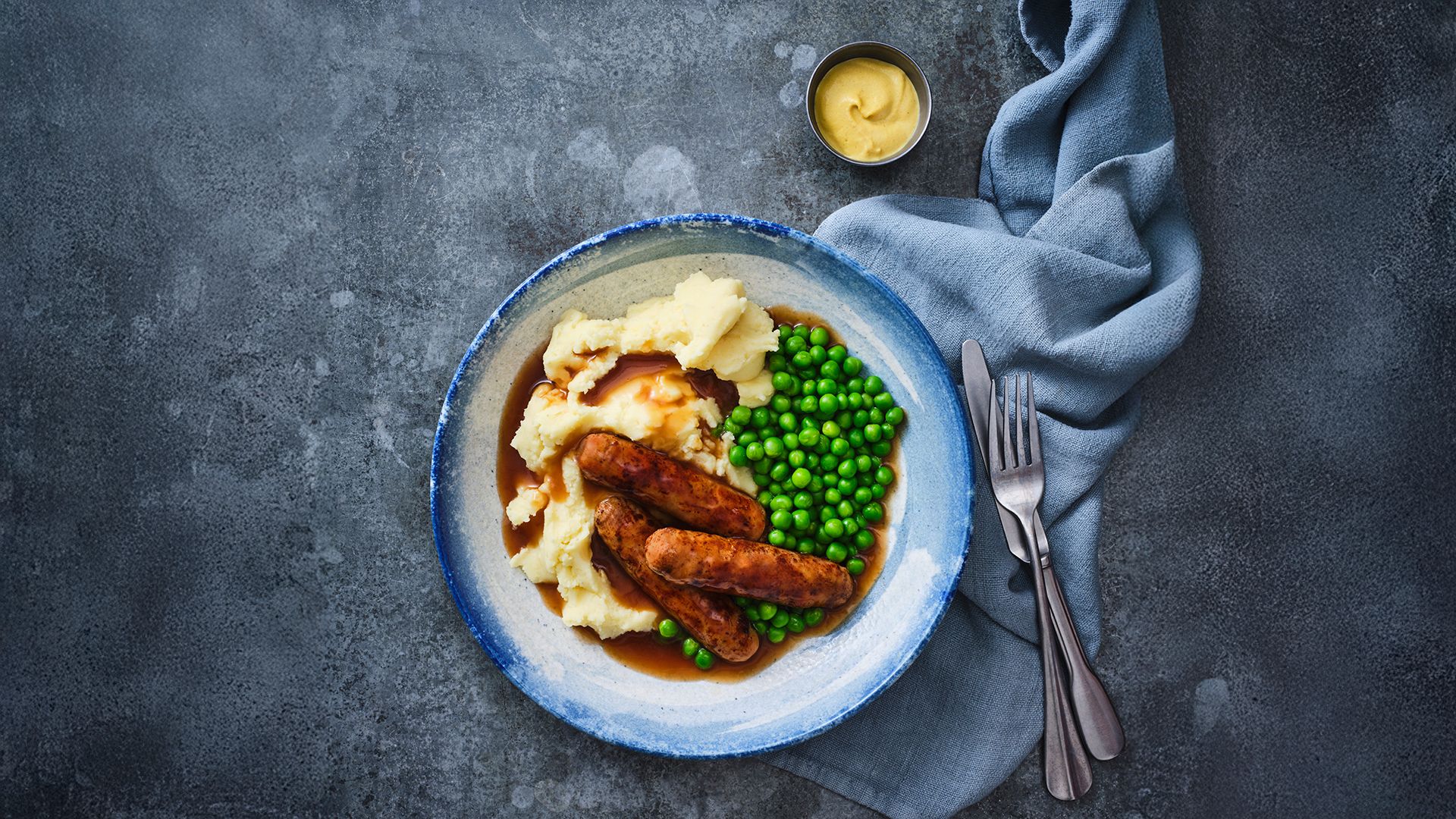 A photo of sausages and mash, served in gravy with peas at the Beachcomber Inn.