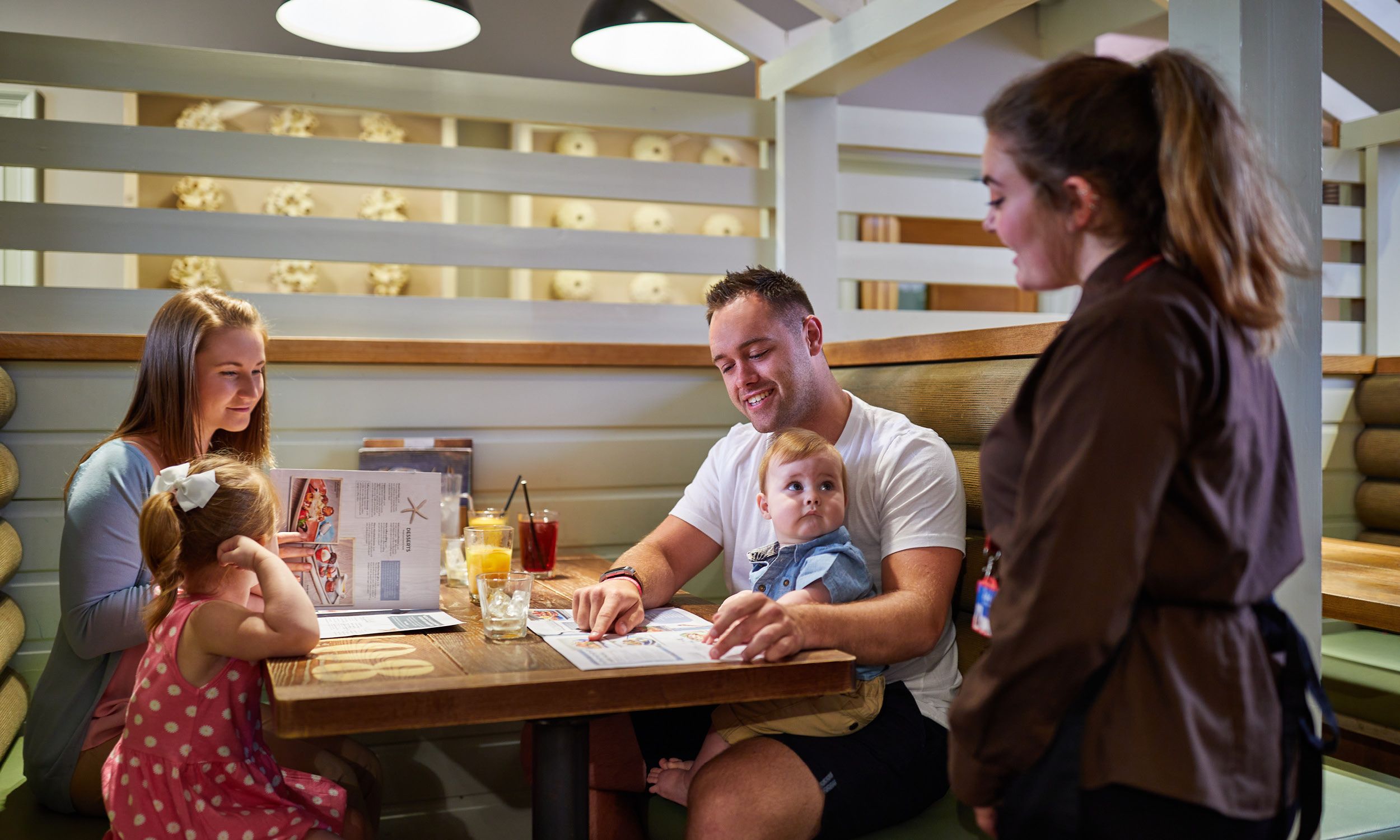 A family sit together at the Beachcomber Inn at Bognor Regis, and are about to place their order with a staff member.