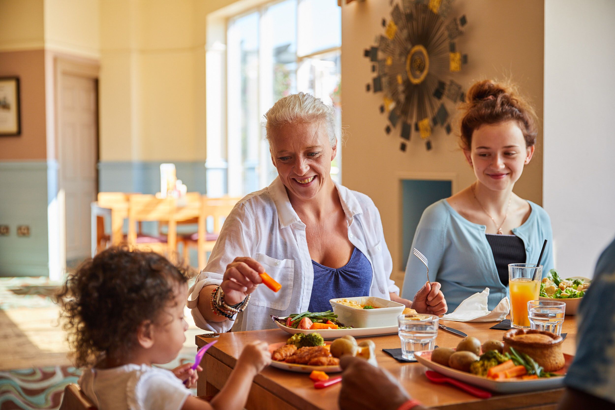 Two woman and a baby having their lunch at the table.