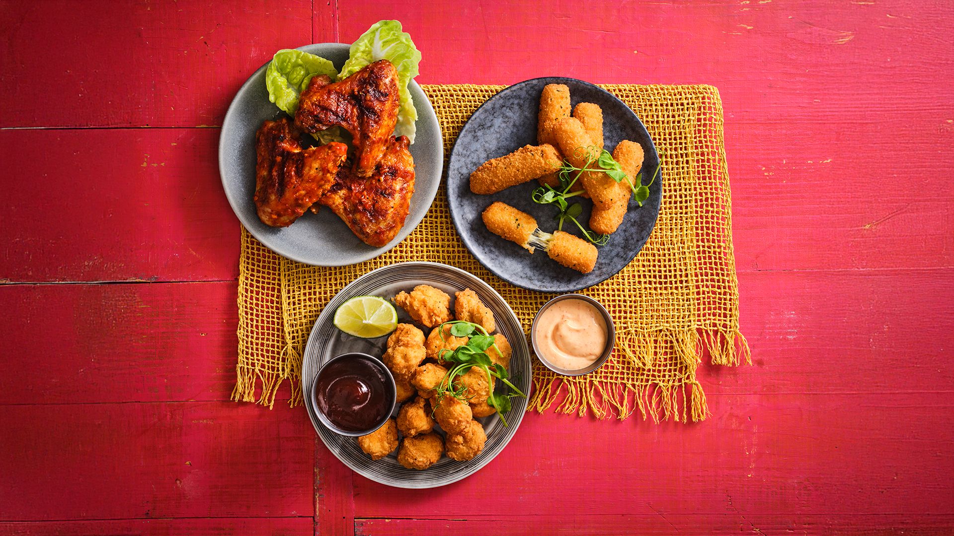 Three dishes offered at the Firehouse Grill are placed on a red table next to each other.