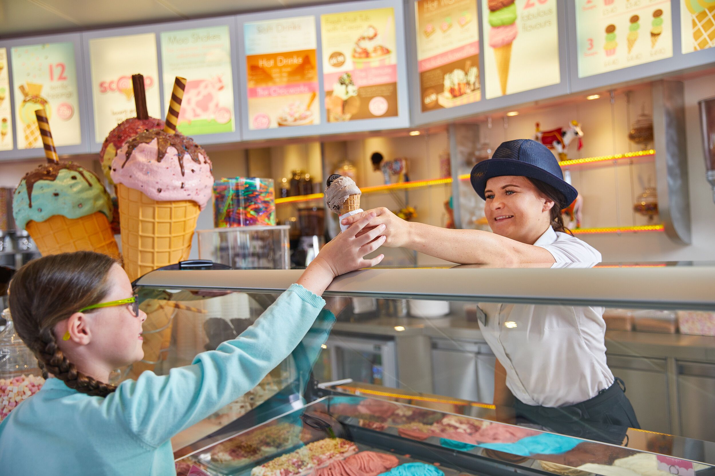 A server handing an ice cream cone to a little girl.