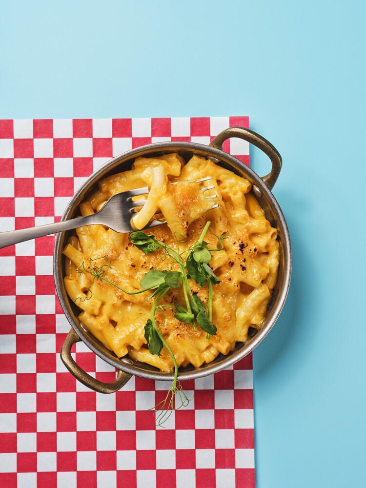 A pot of macaroni cheese garnished with some herbs.