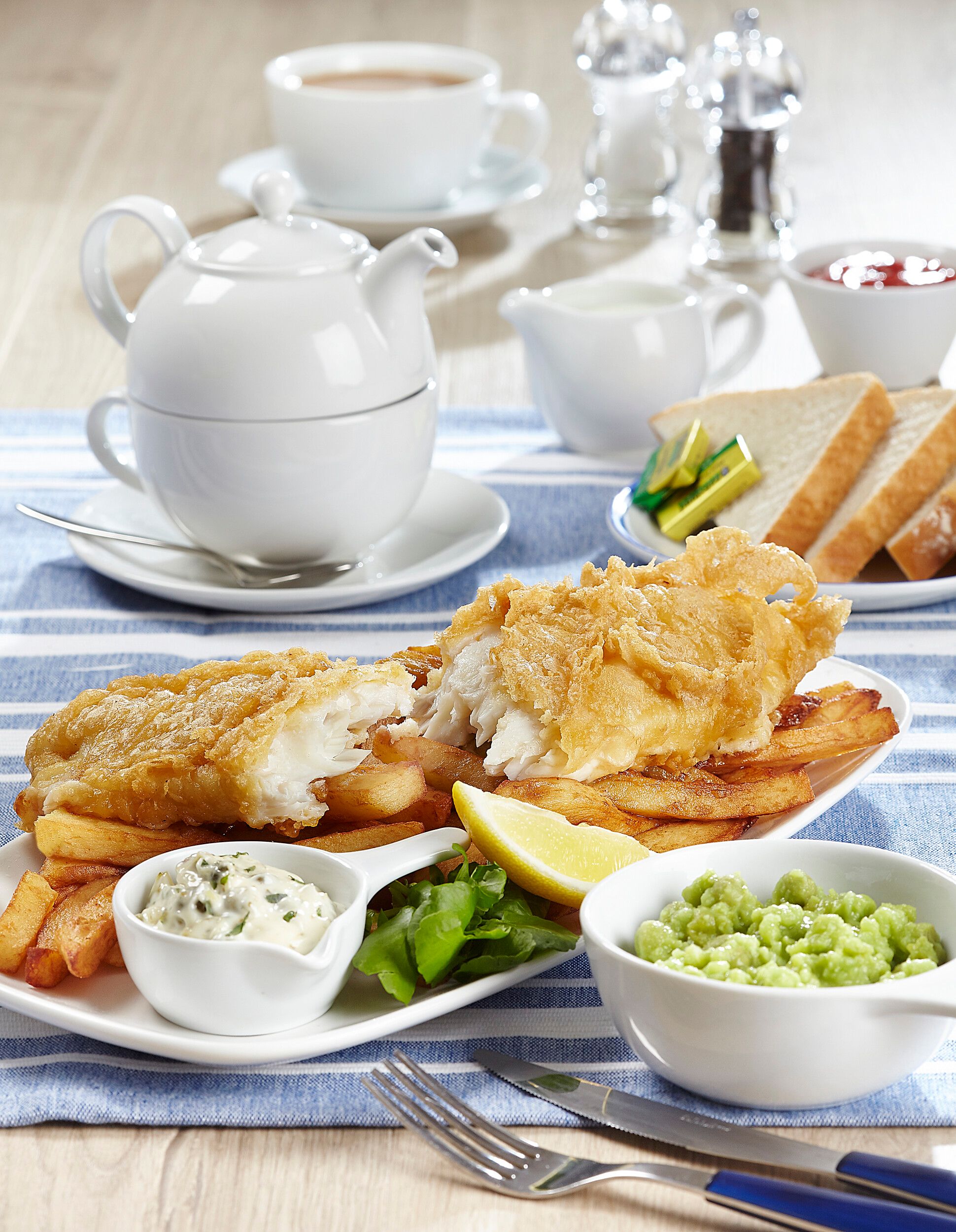 A plate of fish and chips with sauce.