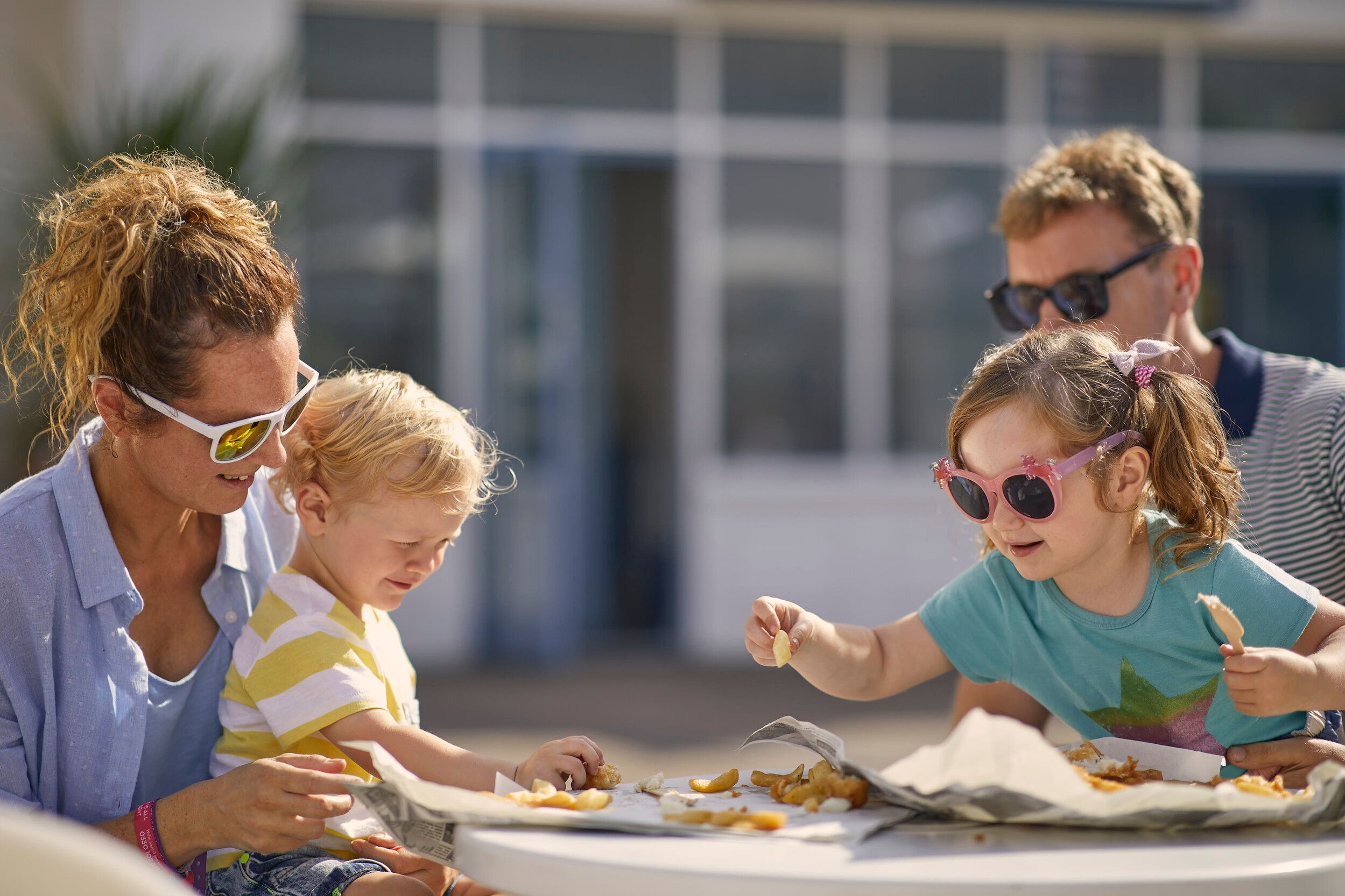 A family of four having their lunch at Butlin's Fish and Chips outdoors.