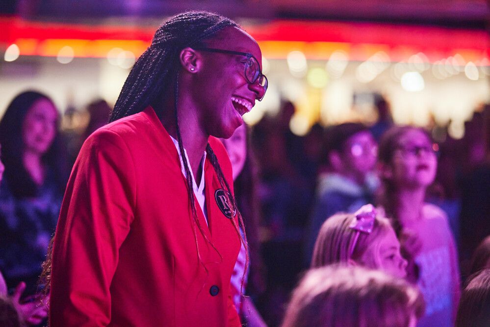 A Redcoat smiles towards the stage, as she stands in amongst the audience during a live show.