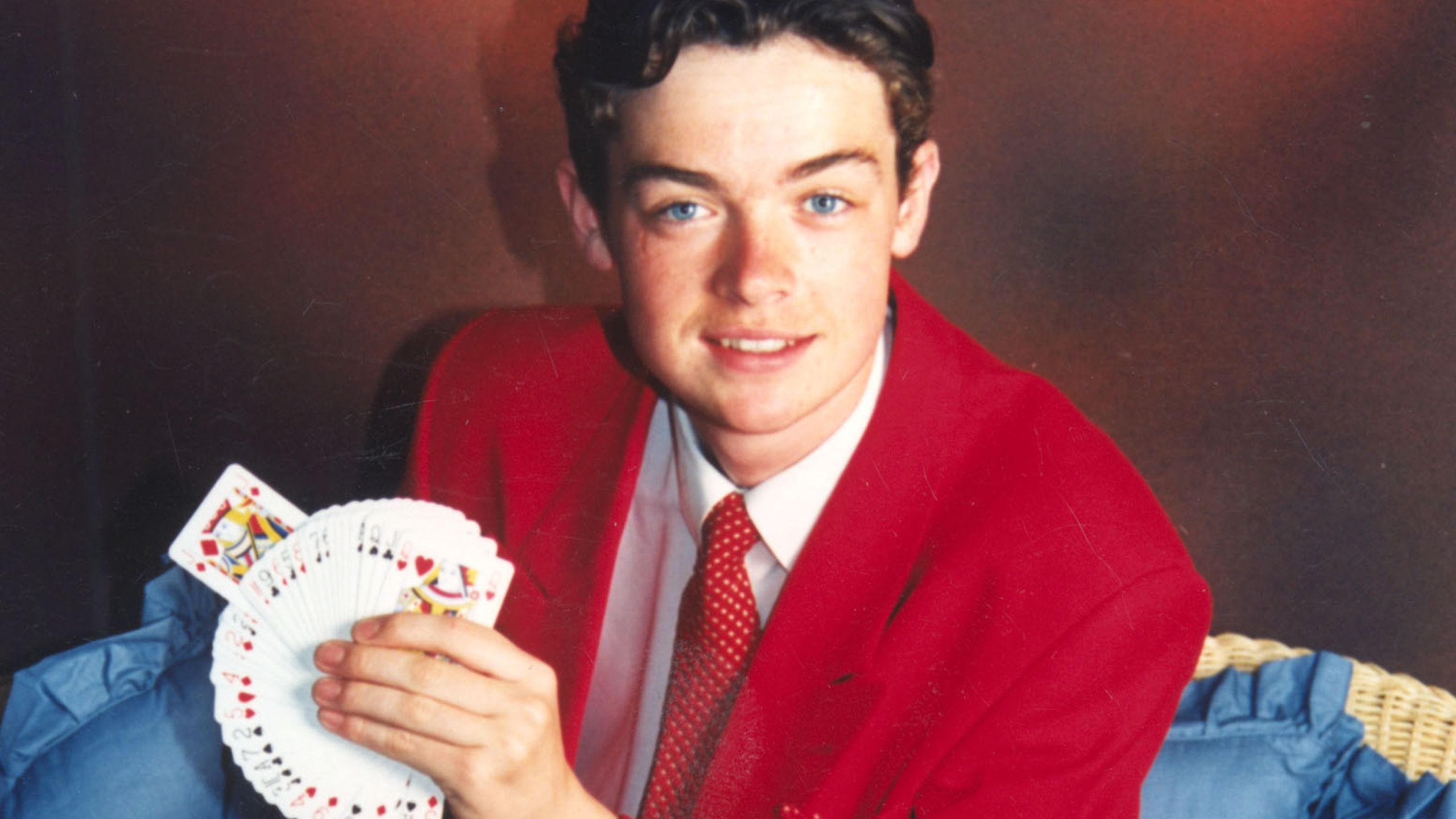 A photo of Stephen Mulhern, when he was a Butlin's Redcoat. He poses for the camera with a deck of cards in his hand.