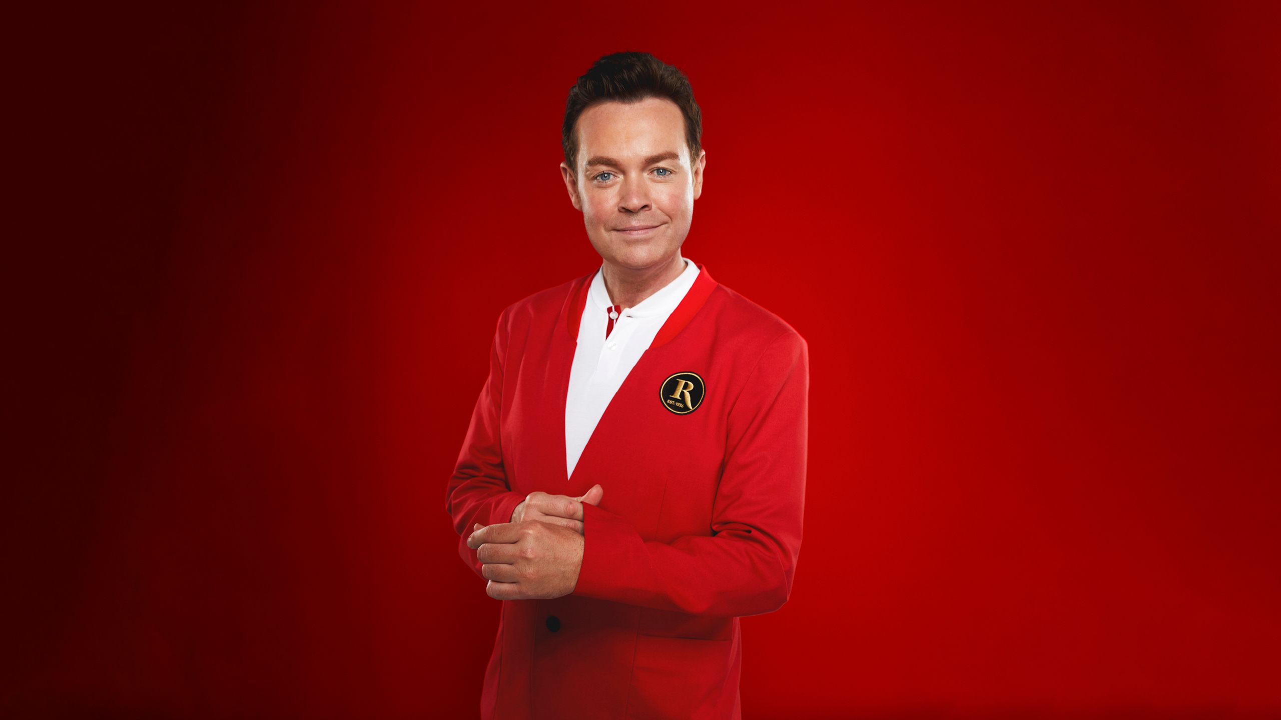 Stephen Mulhern poses for the camera while wearing a Butlin's Redcoat uniform.