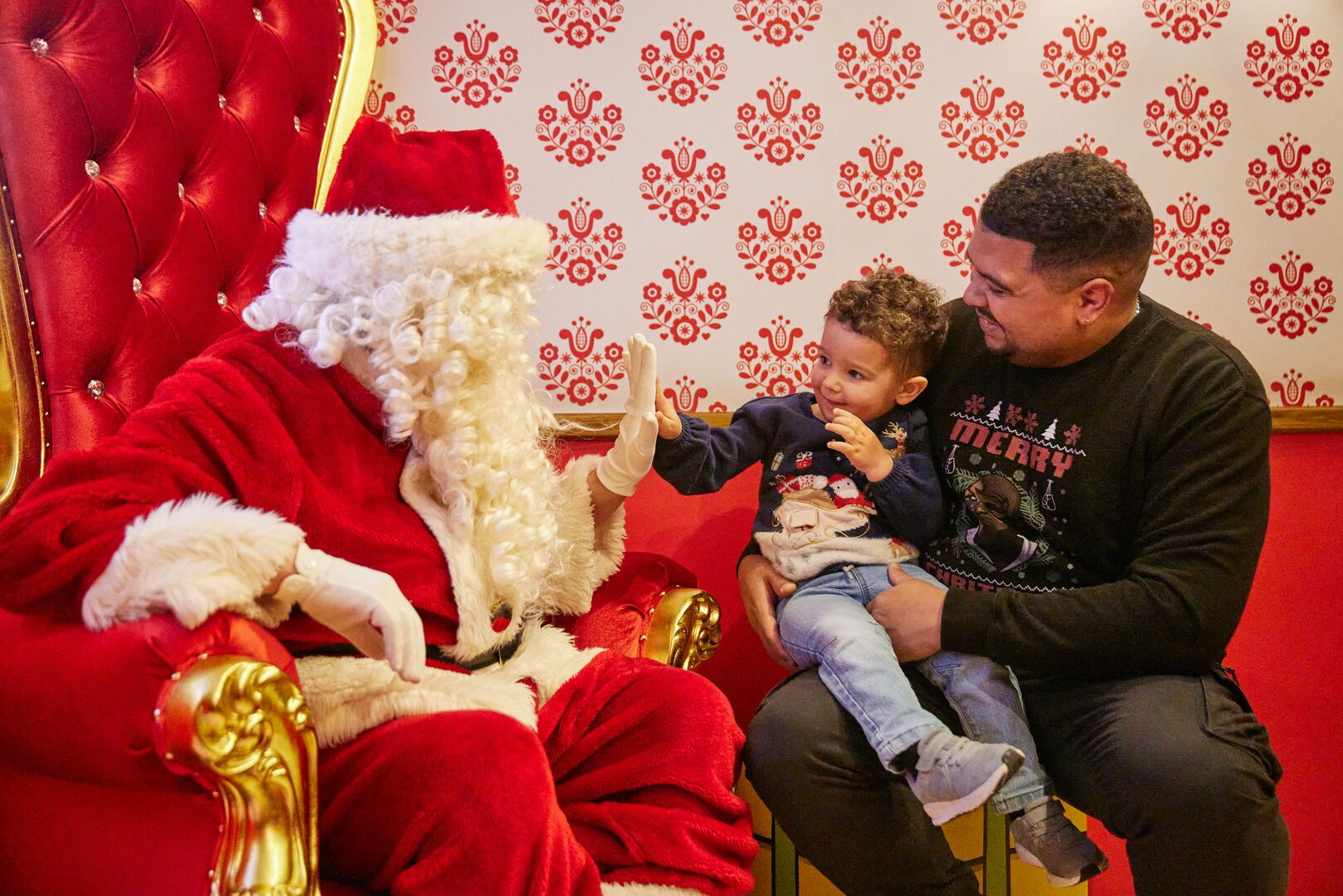 A father sits with his son, as they meet Father Christmas.