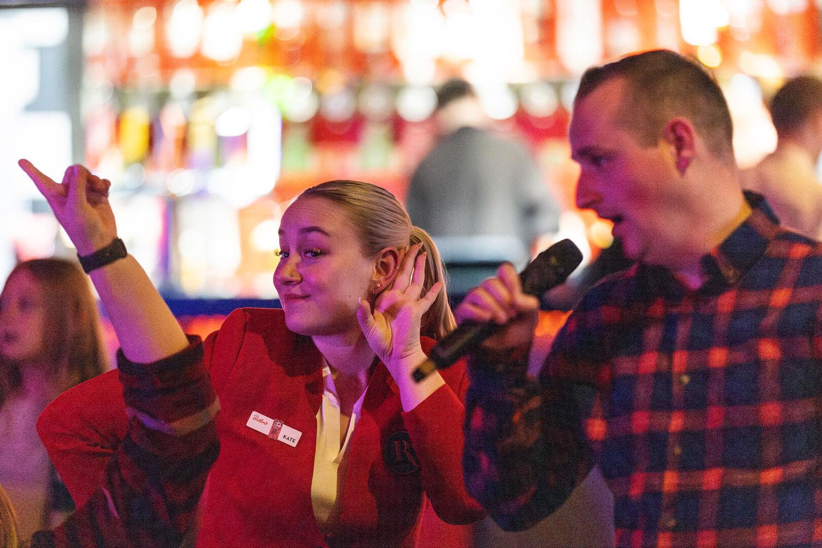 Butlin’s team member joins in the fun, encouraging a guest holding a microphone during a lively festive entertainment session.