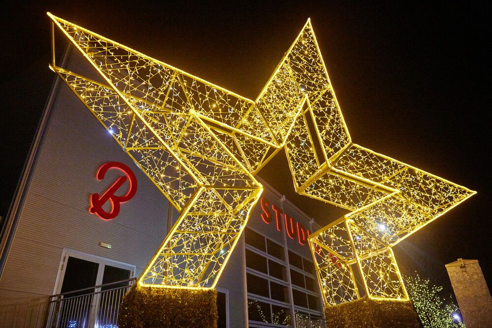 A large illuminated star-shaped Christmas decoration made of golden fairy lights stands in front of the Studio 36 venue building, taken at night.