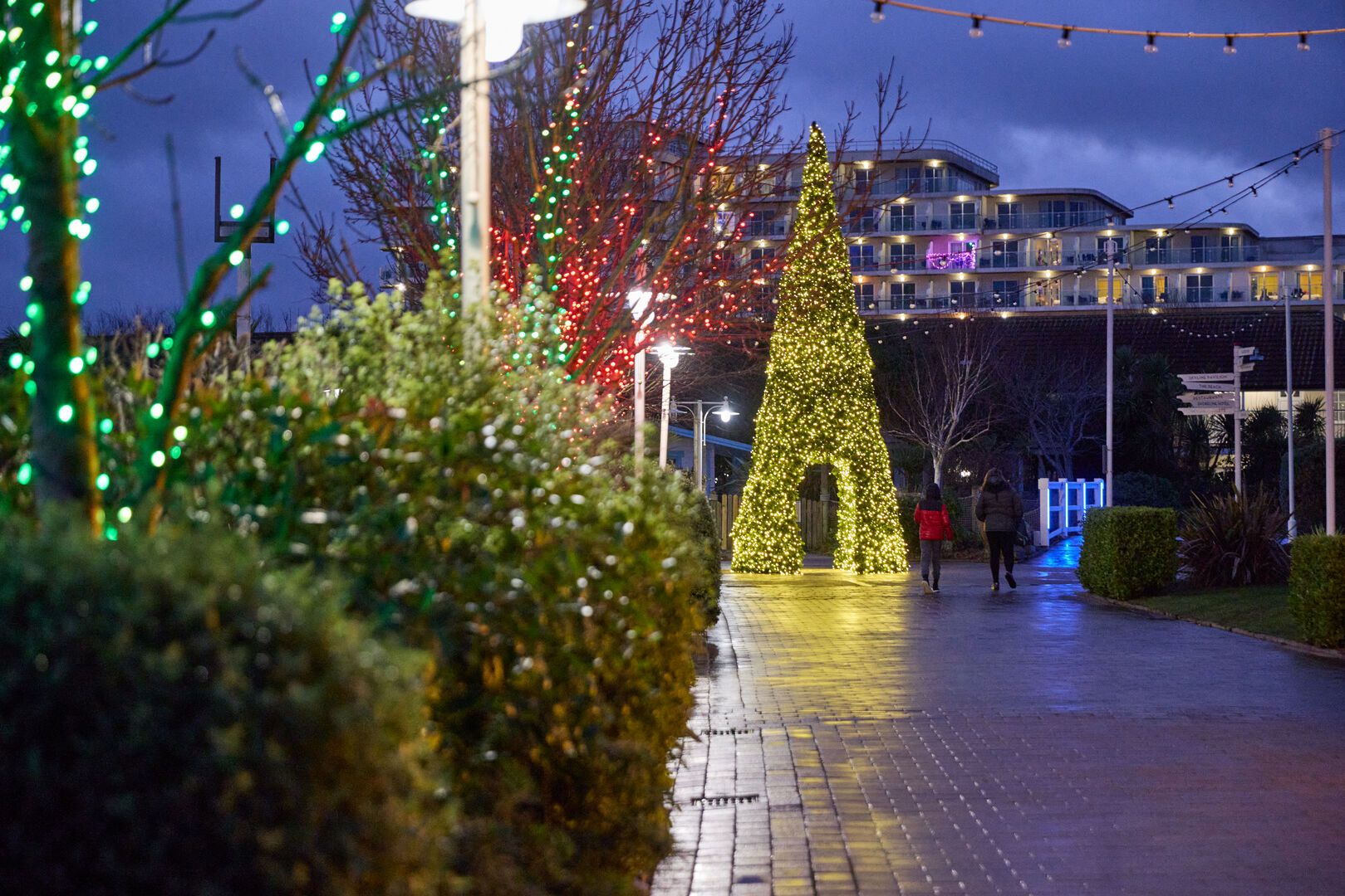 Christmas tree-shaped light tunnel and colourful fairy lights along a pathway at Butlin’s family resort.