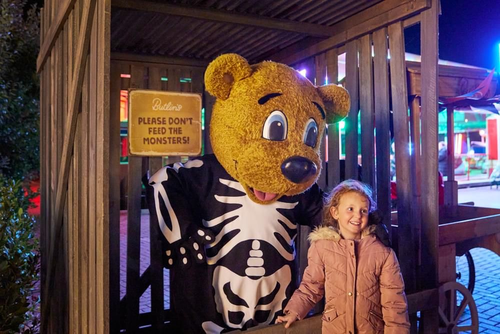 Billy Bear wearing a skeleton costume and a girl posing at the camera.