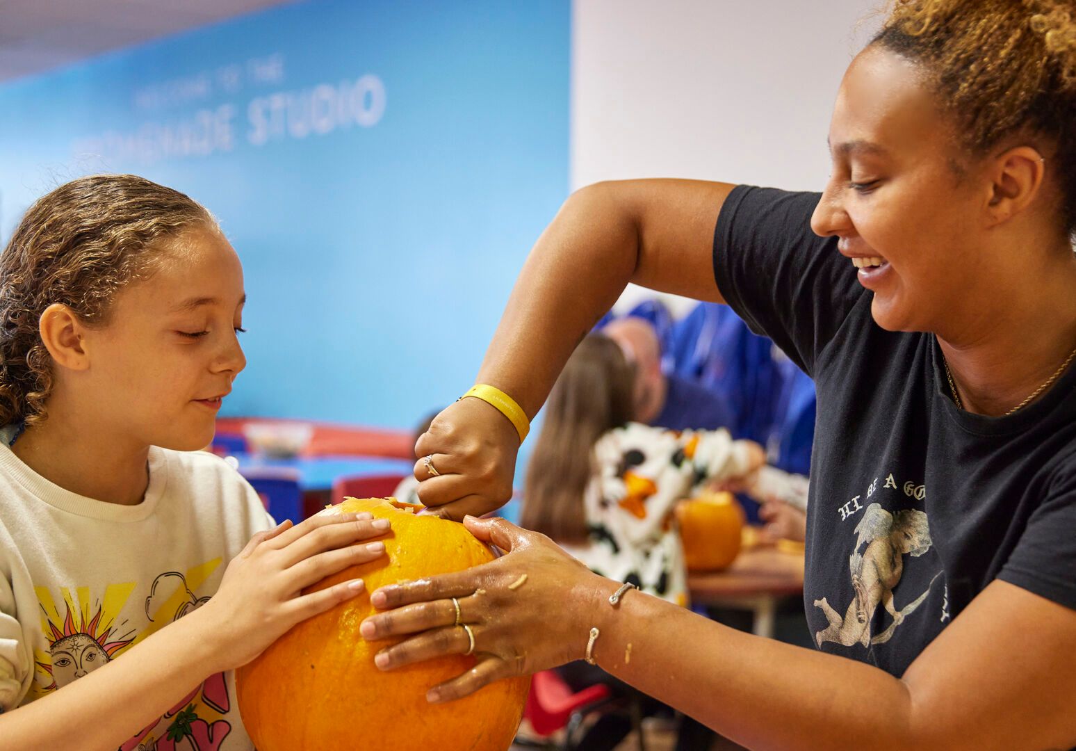 A mother and child scoop out the insides of the pumpkin to create a Jack-o'-lantern during the Pumpkin Carving activity.