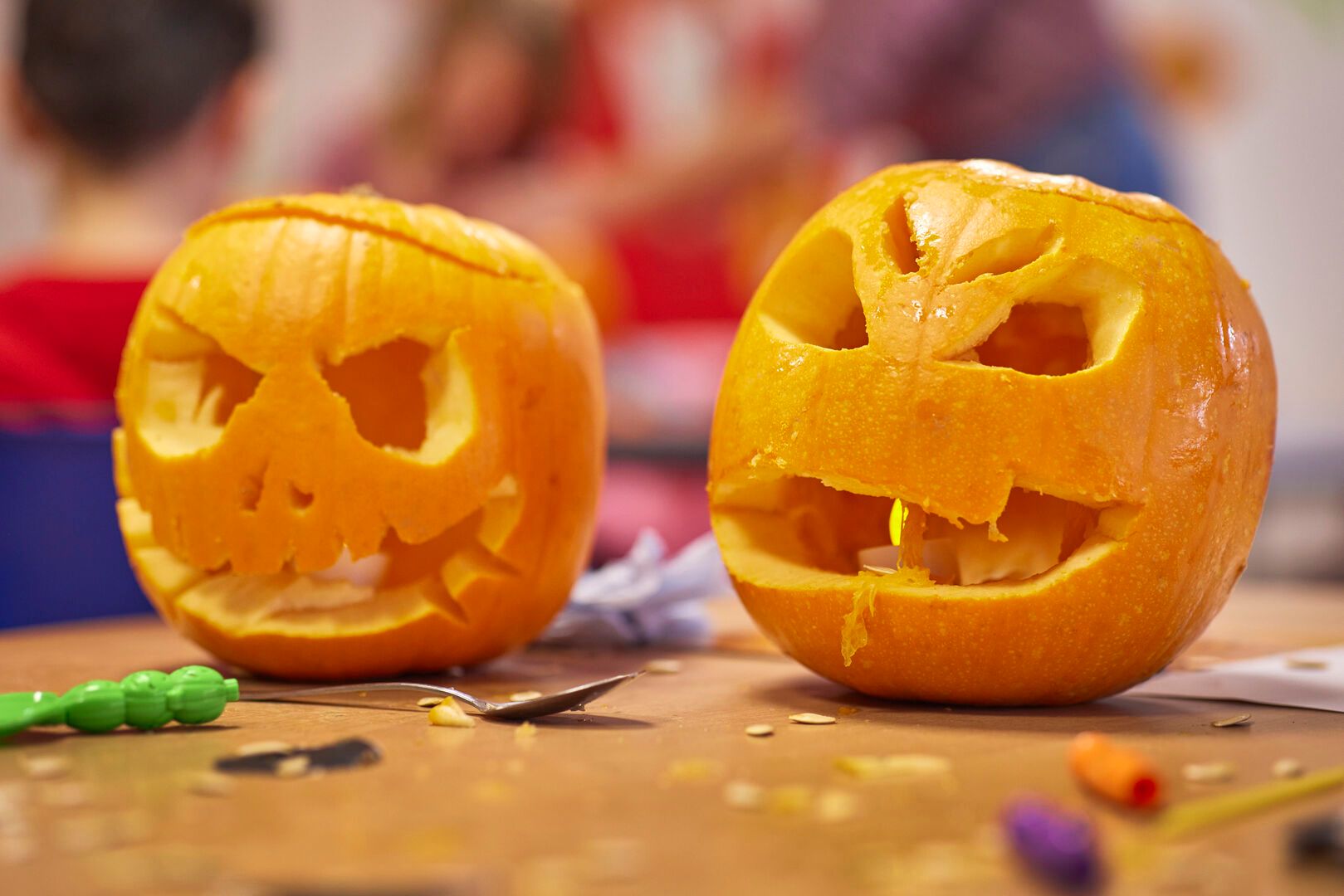 A close up of two carved pumpkins with scary faces for Halloween.