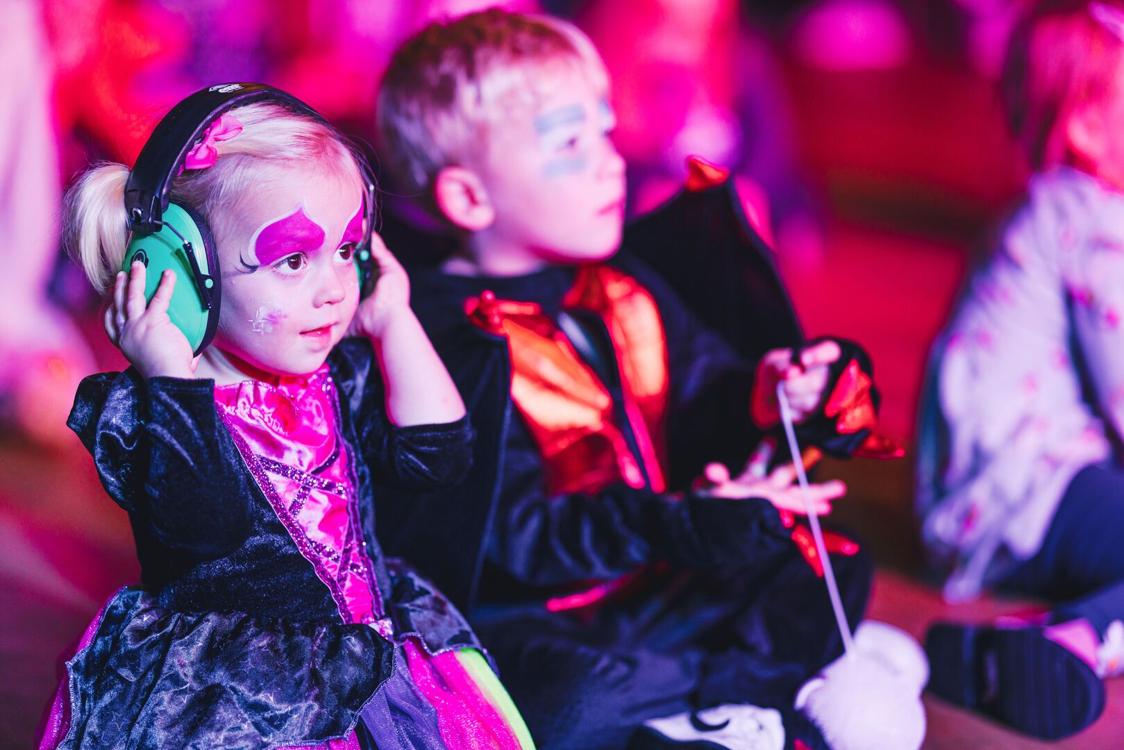 Two young children watch a show during a Halloween break.