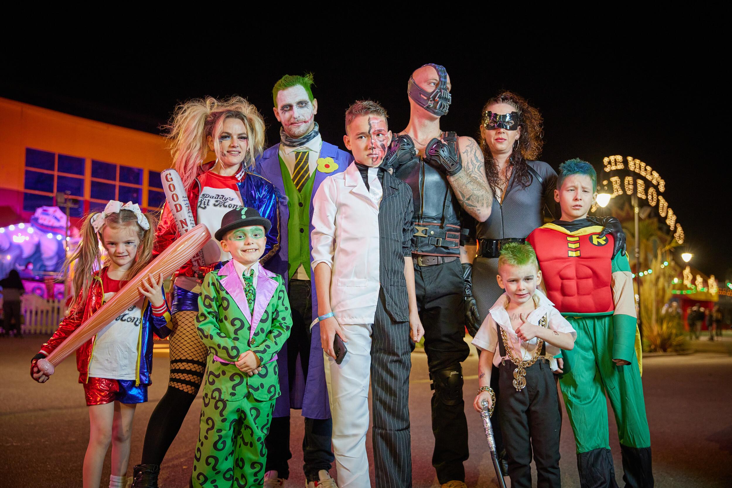 Family and children dressed as comic book villains and superheroes posing in costume.