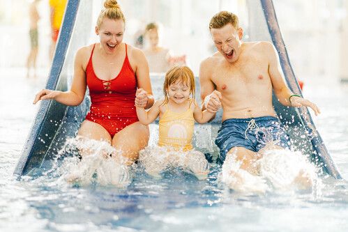 A mother and father go down the slide with their young daughter at Bognor Regis Splash Waterworld.