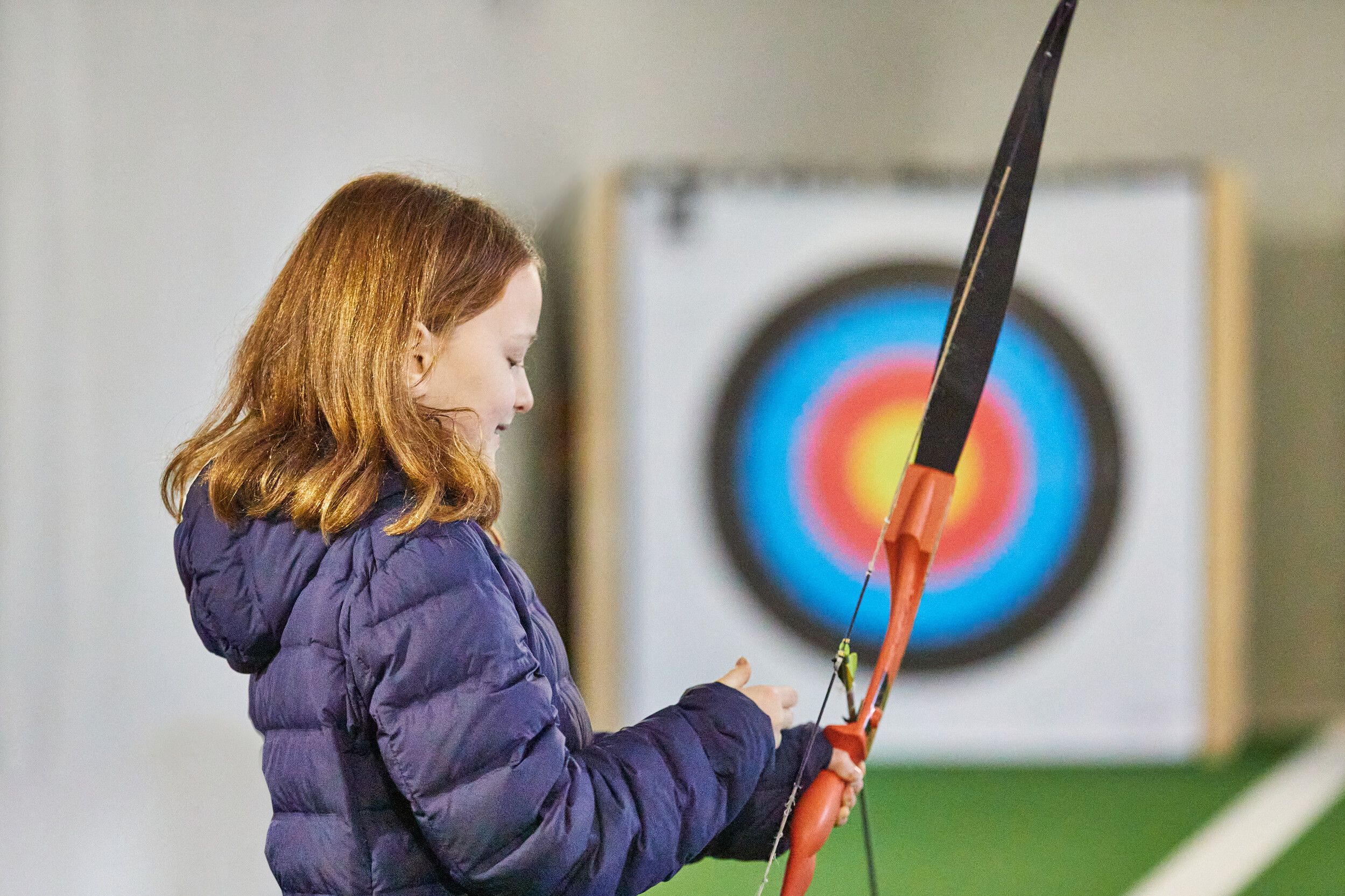 A girl preparing to take a shot in an Archery range.
