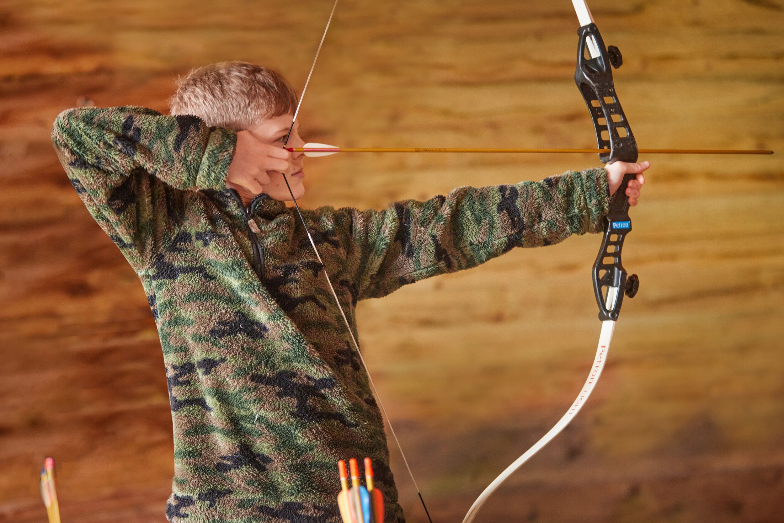 A boy aiming at a target with a bow and arrow.