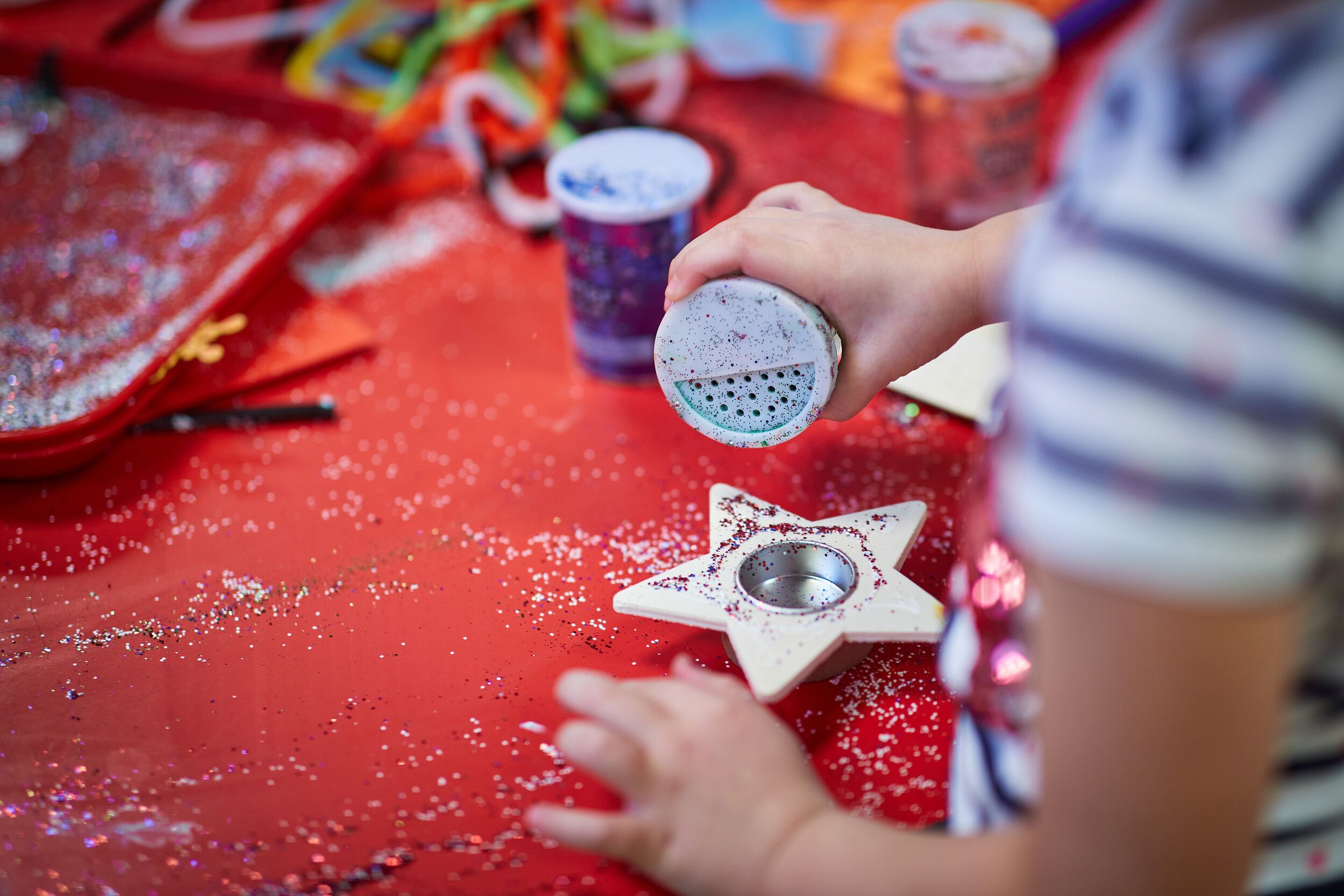 A kid pouring some glitters in a container.
