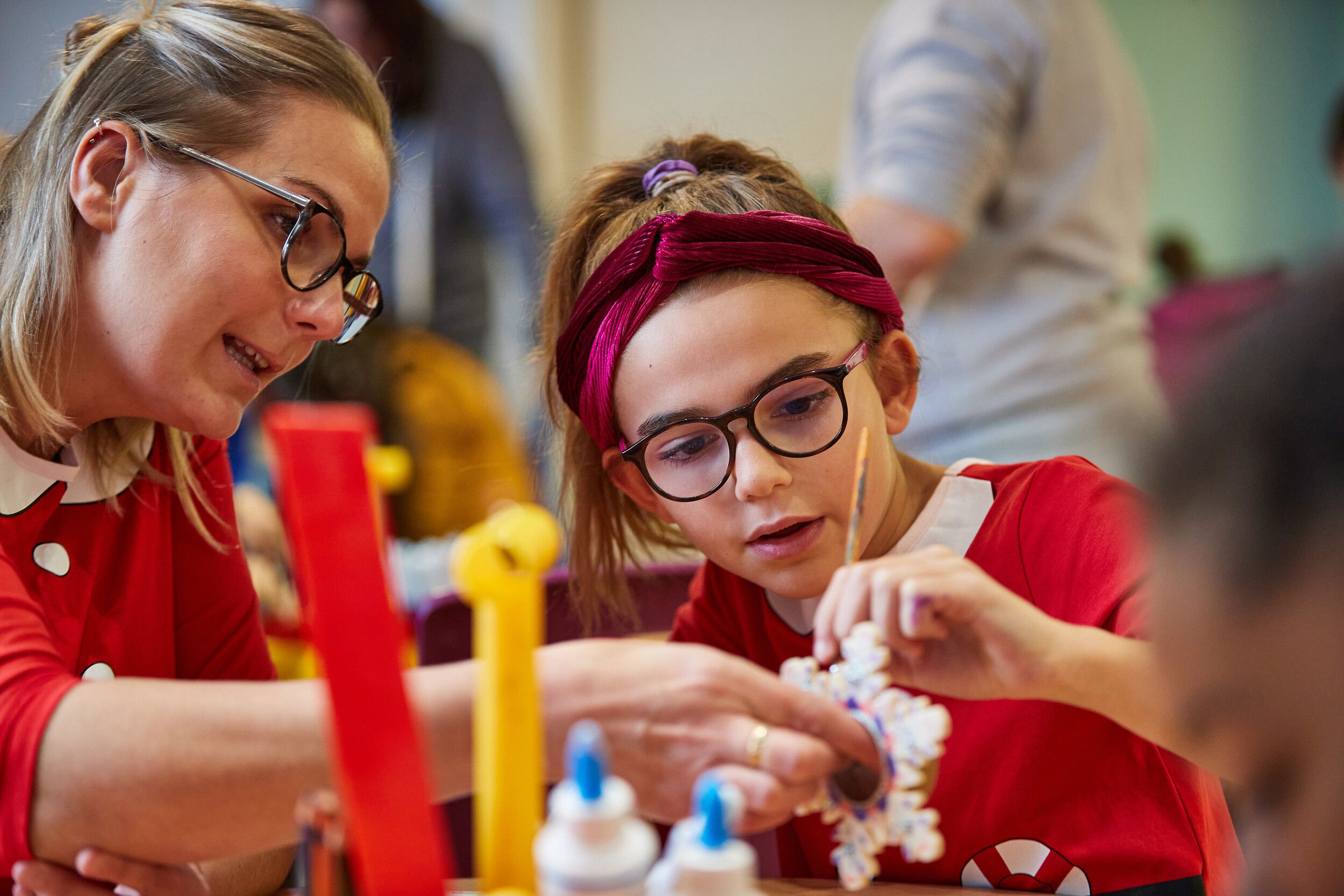 A staff and girl painting some artwork.