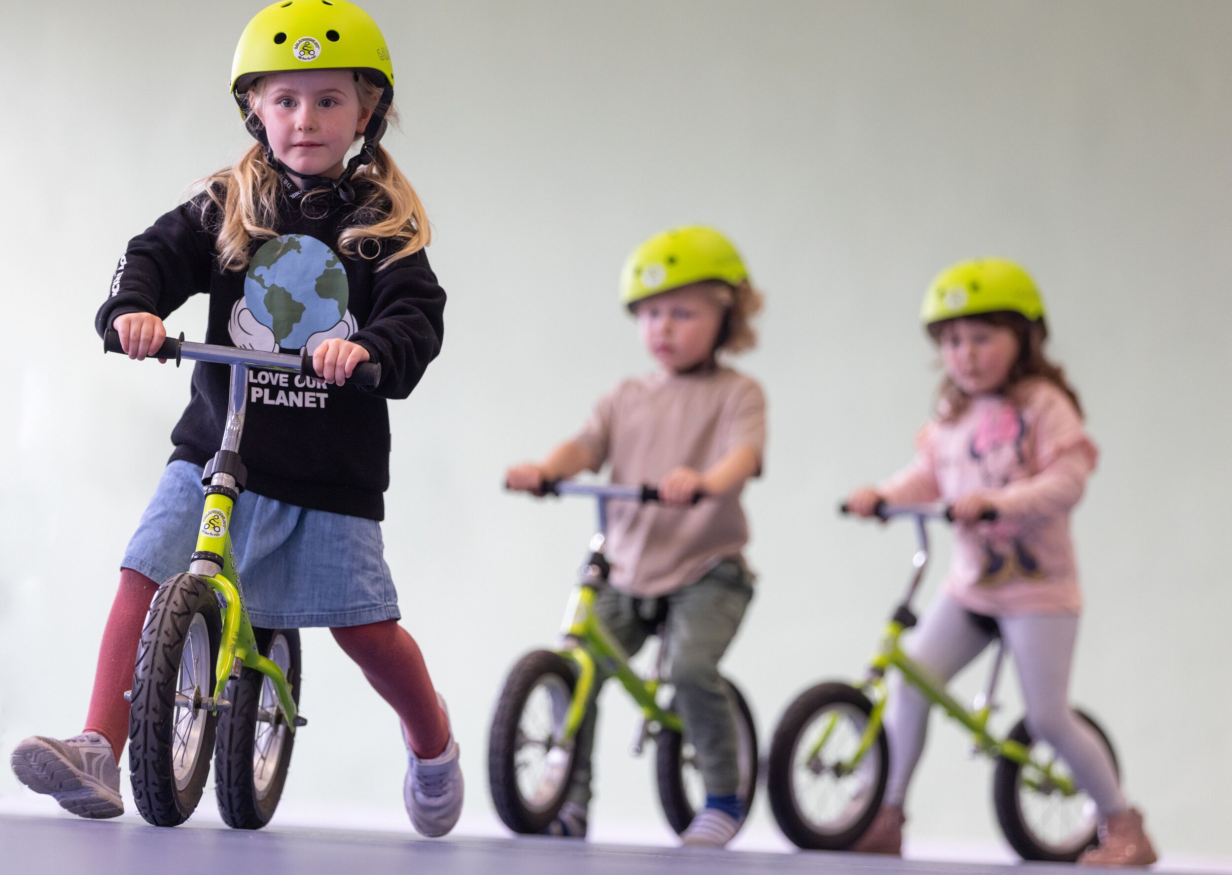 Three children with helmets while riding a bicycle.