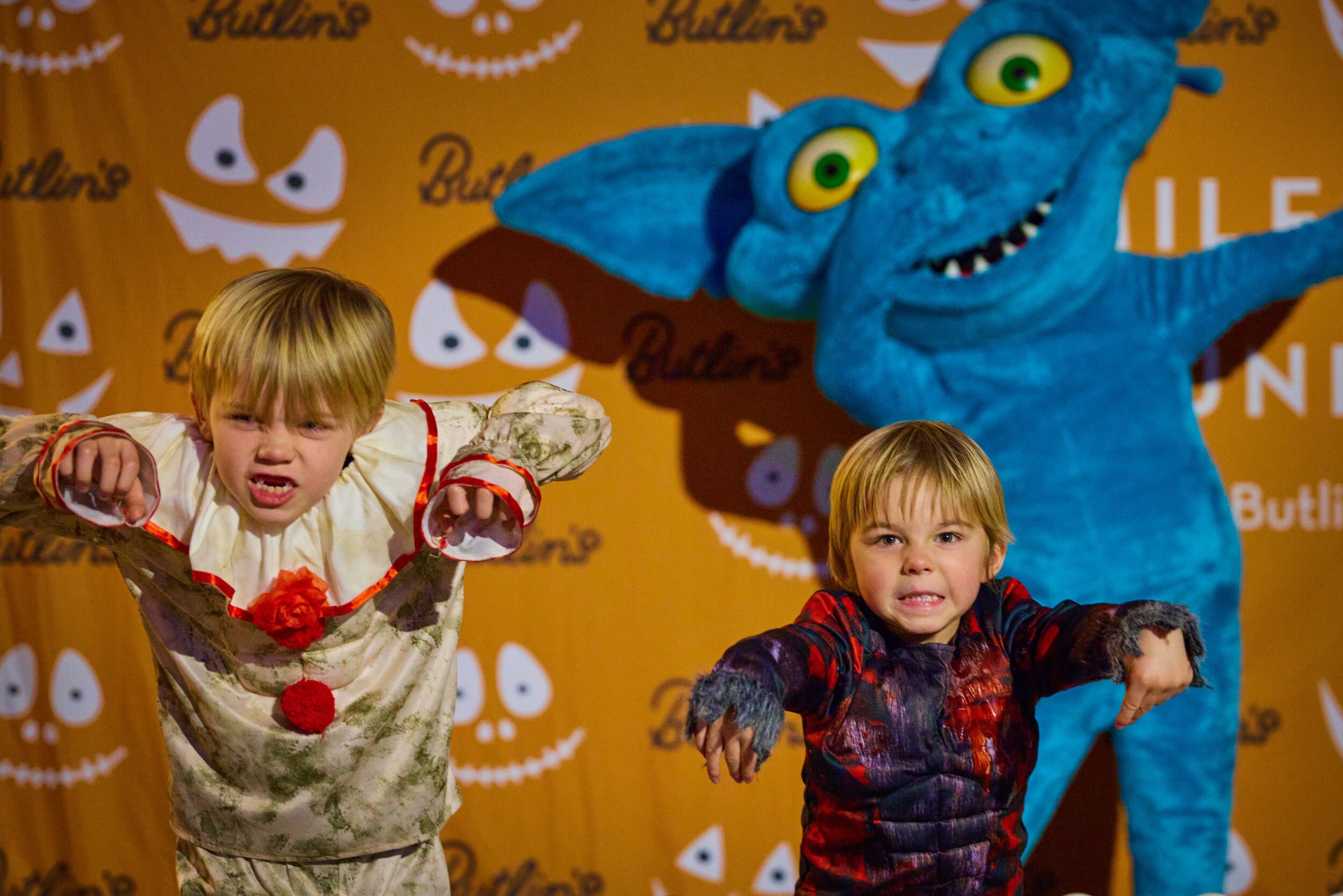Two children and a blue mascot posing at the camera.