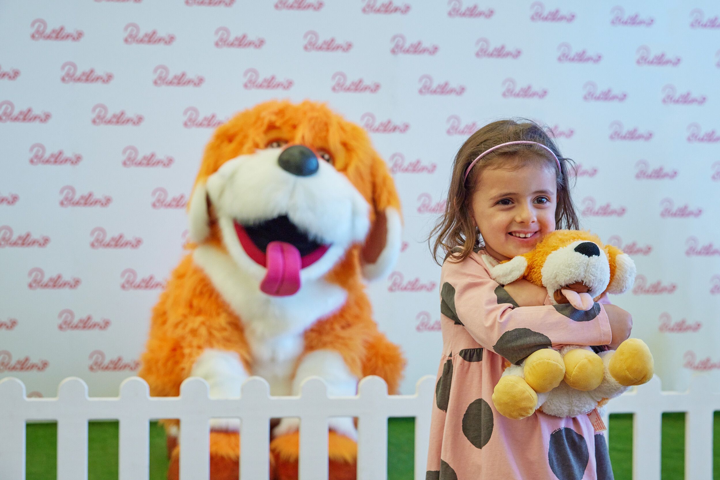 A little girl posing at the camera with Rainbow the dog.
