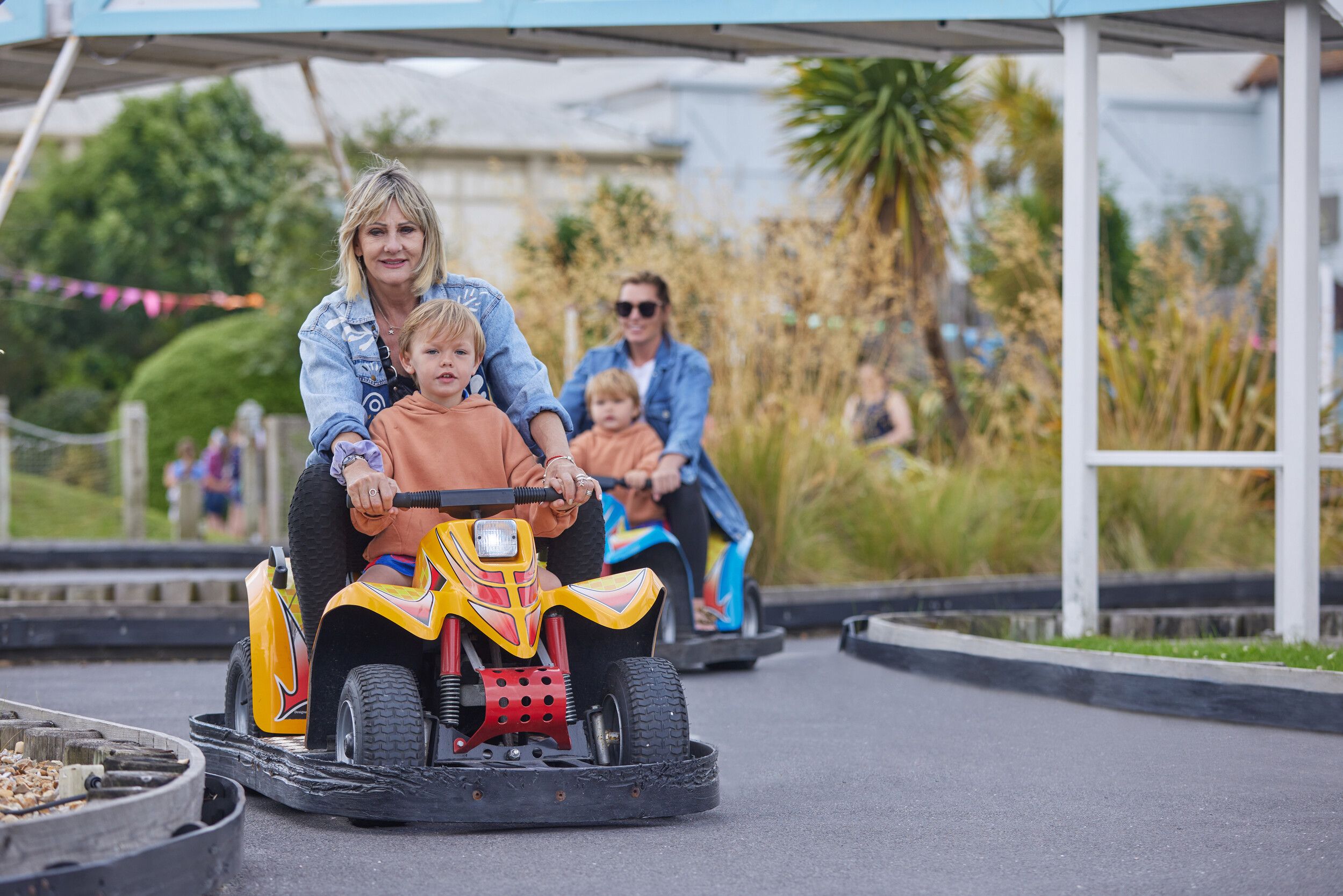 Two mothers teaching their children how to drive in a driving school.
