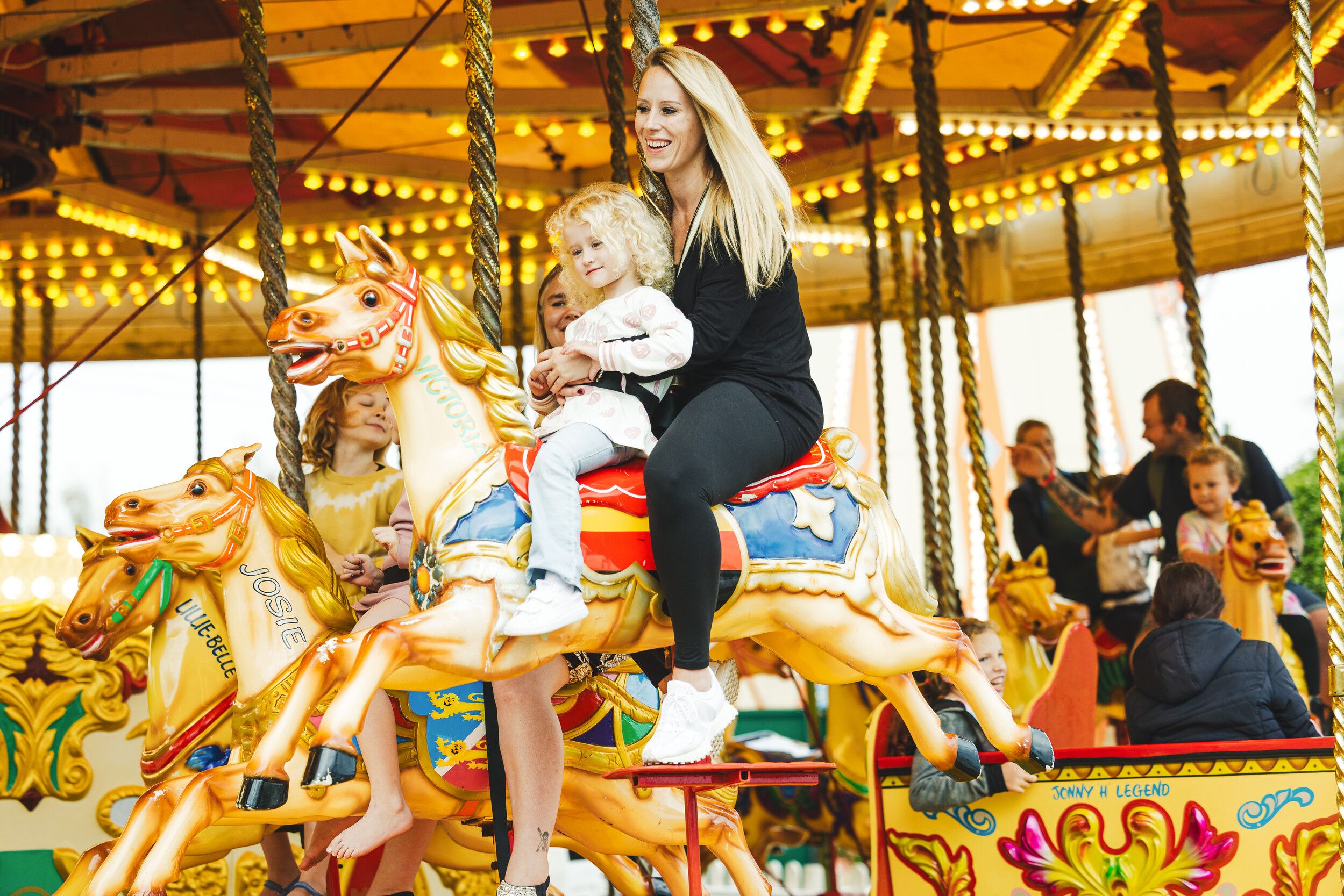 A woman and a child riding the carousel at the fairground.