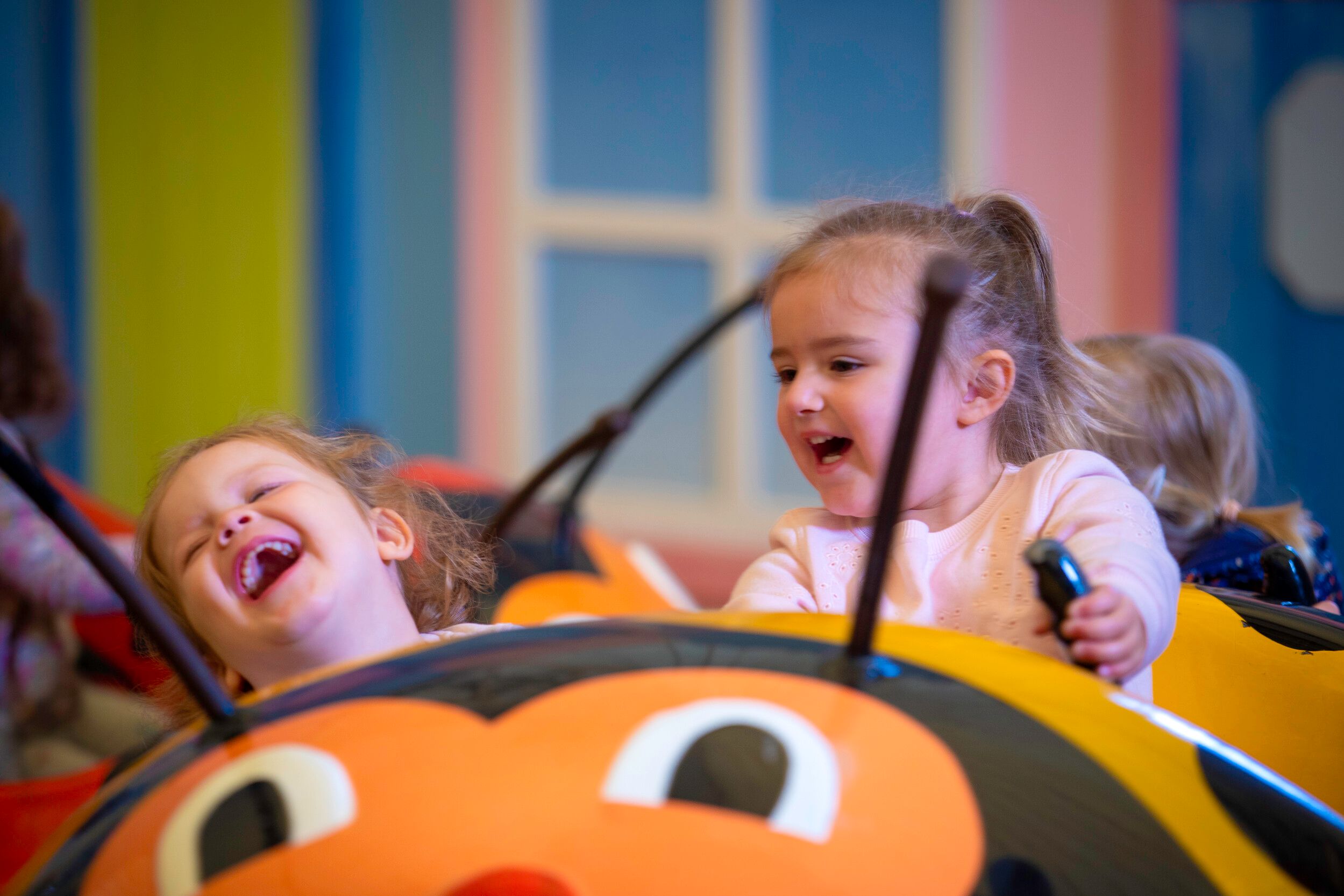 Two tots laugh while on a Little Stars fairground ride.