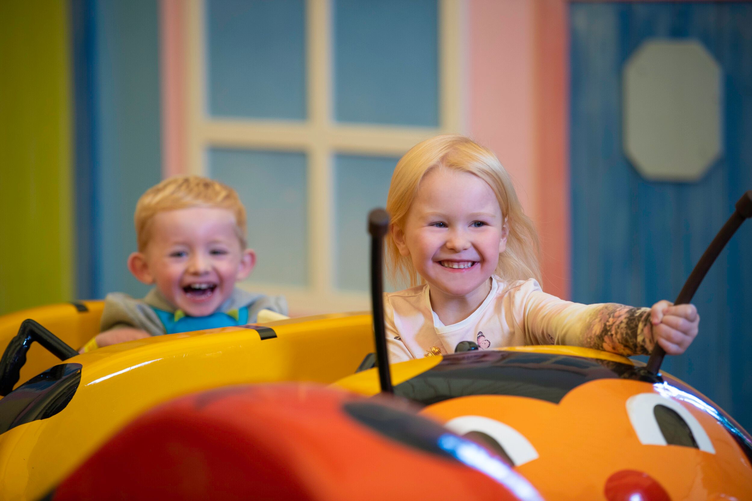 Two tots laugh and smile while on a Little Stars fairground ride.