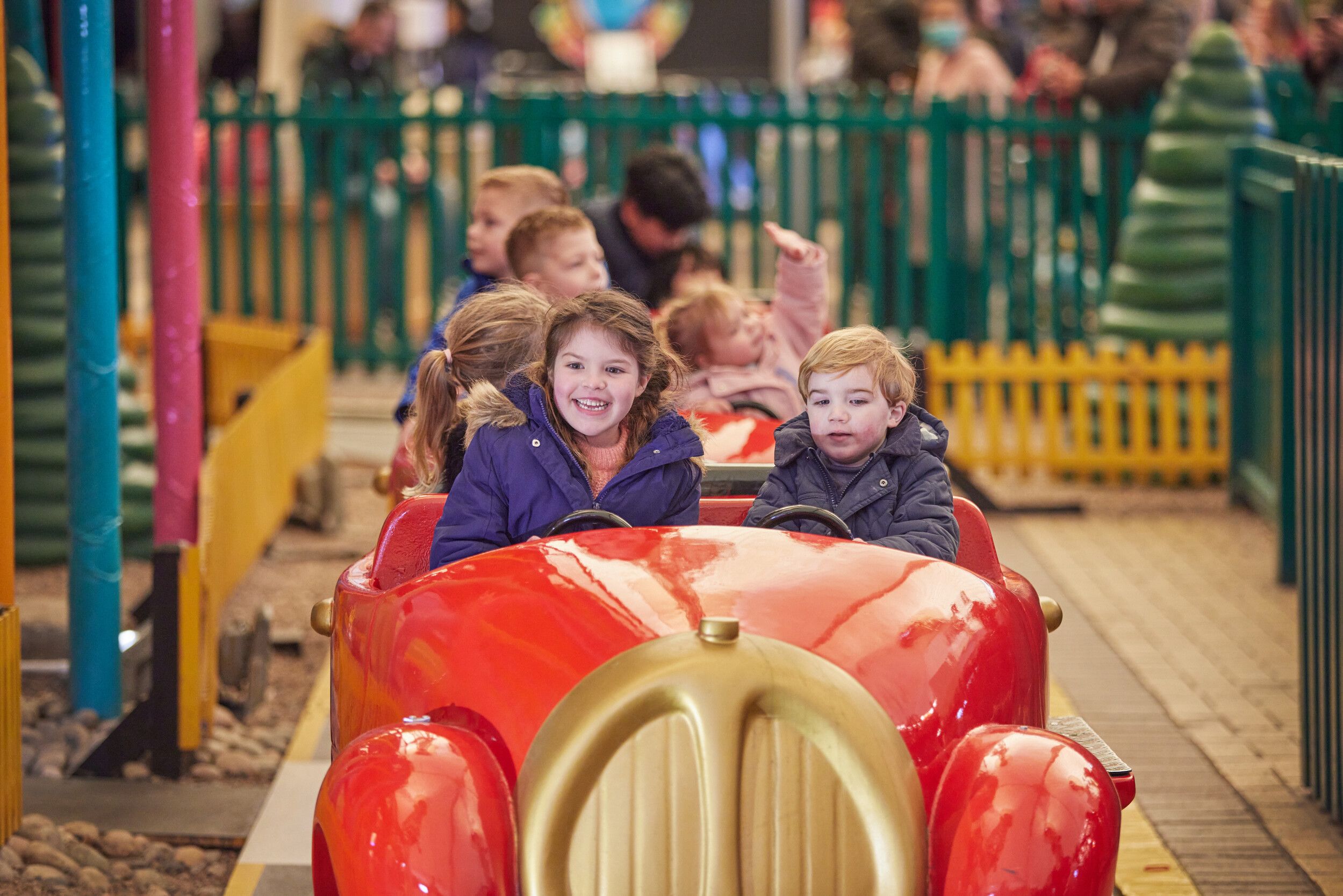 A group of children riding a toy train at the fairground.