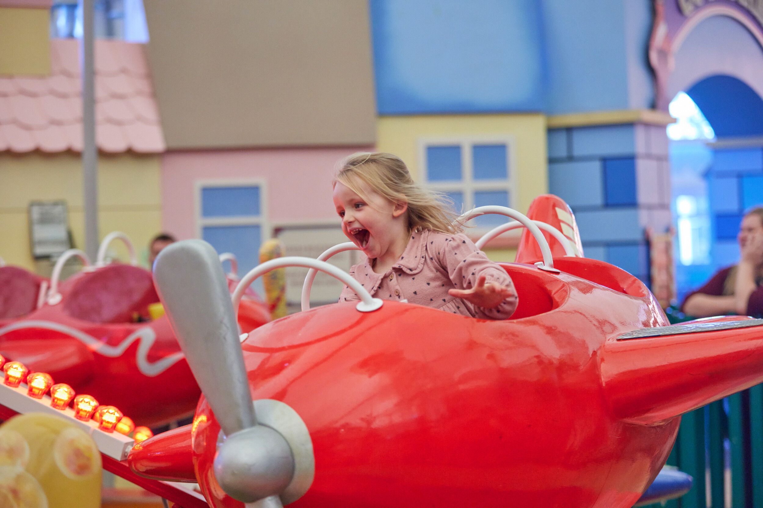 A little girl shouting with joy while on a plane fairground ride.