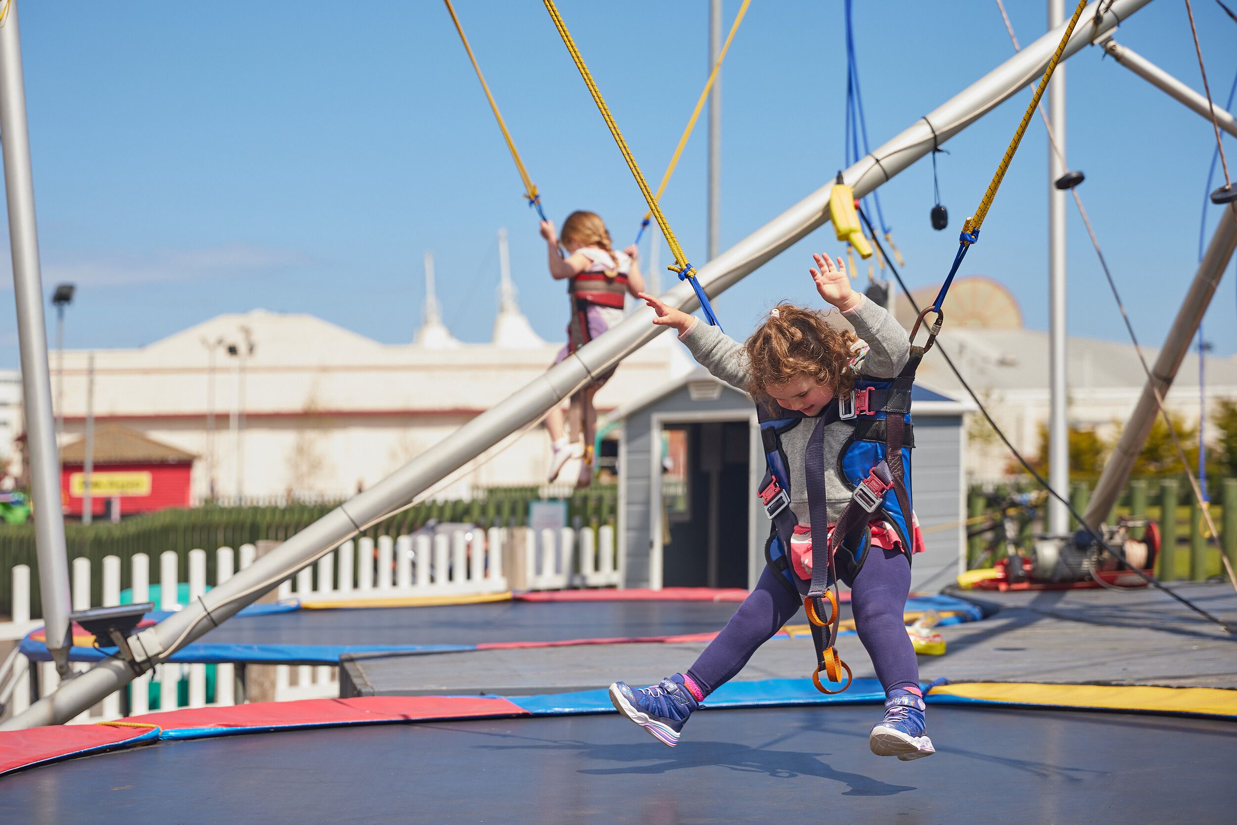 A young girl jumping on a trampoline in the Skegness fairground.