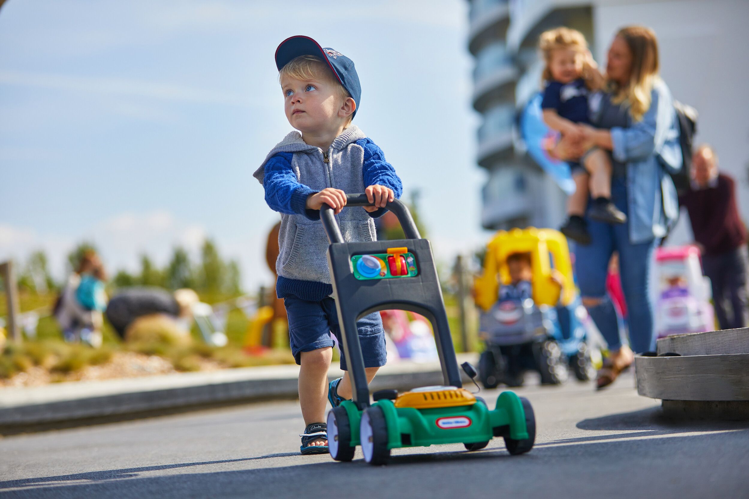 A little boy pushing a toy while looking away.