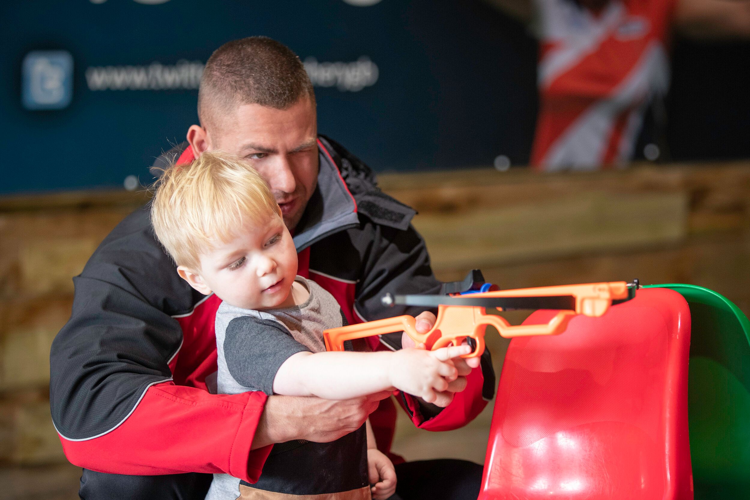 A father teaching his child how to use a mini bow.