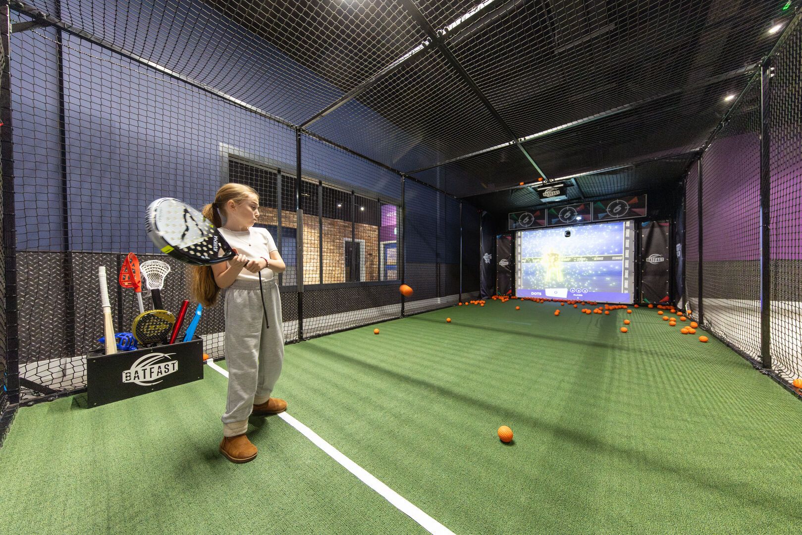 A young girl ready to hit the ball at the Batting Cage in Playxperience.