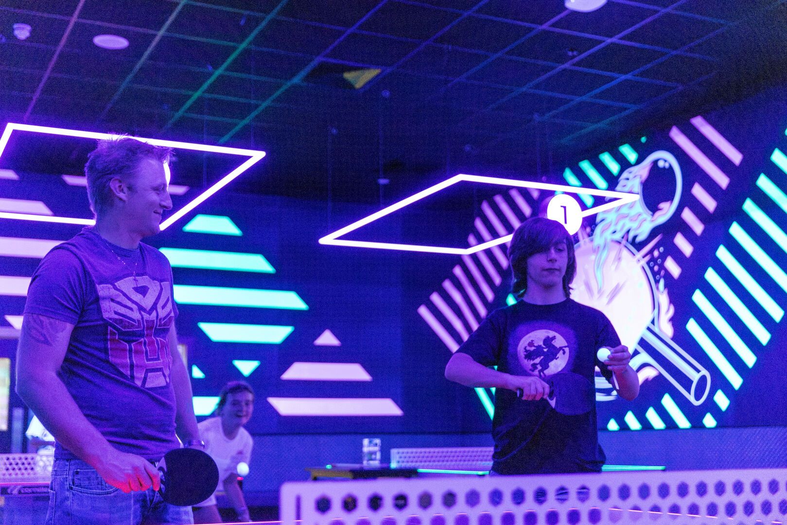 A father and son play Glow Pong together.